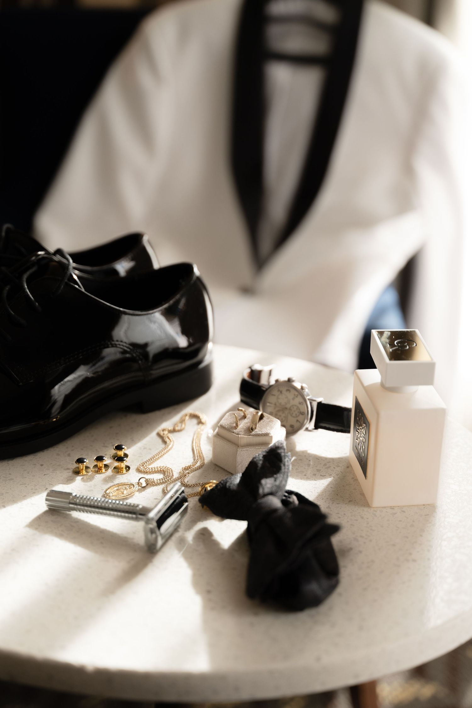 Wedding accessories including shoes, jewelry and cufflinks arranged in dramatic lighting.
