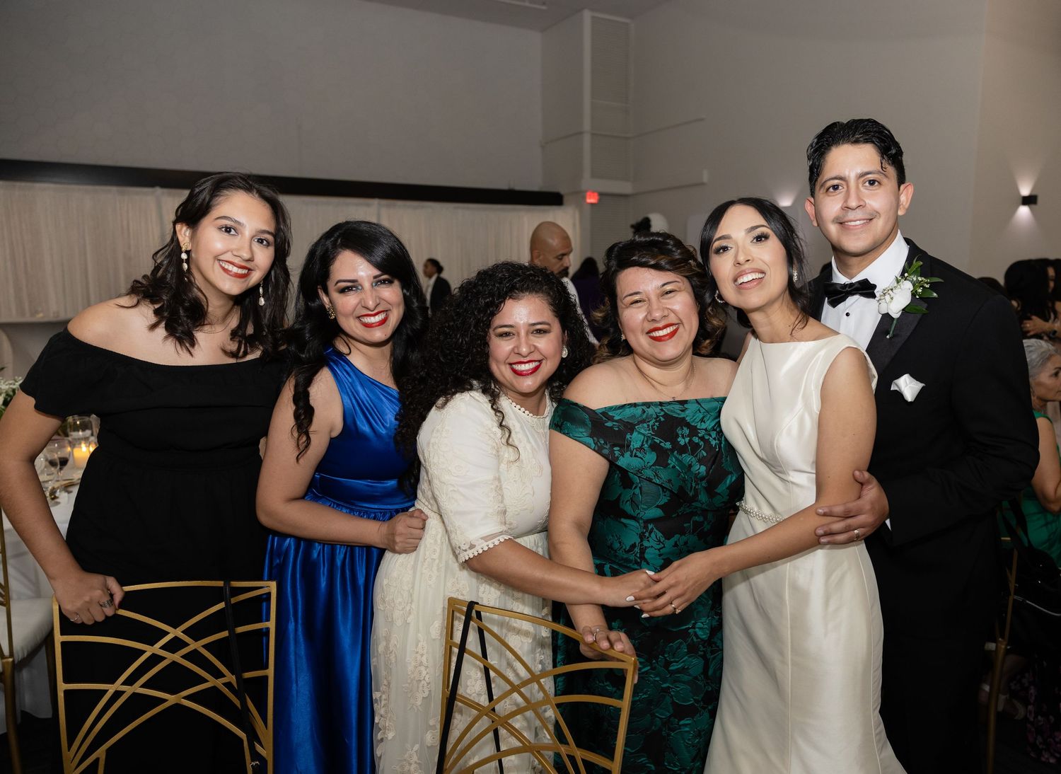 Wedding party members in blue and emerald dresses enjoying themselves on the dance floor.