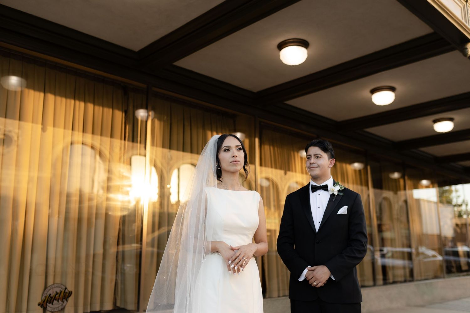 Elegant couple shares intimate moments in a warmly lit indoor venue with wooden beam ceiling.