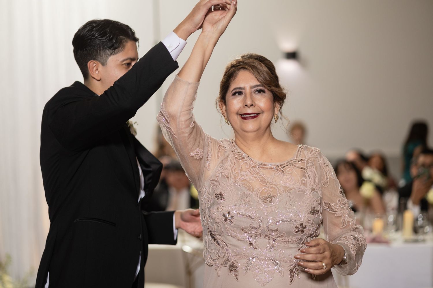 Dance partners twirl and smile during a joyous wedding reception celebration.