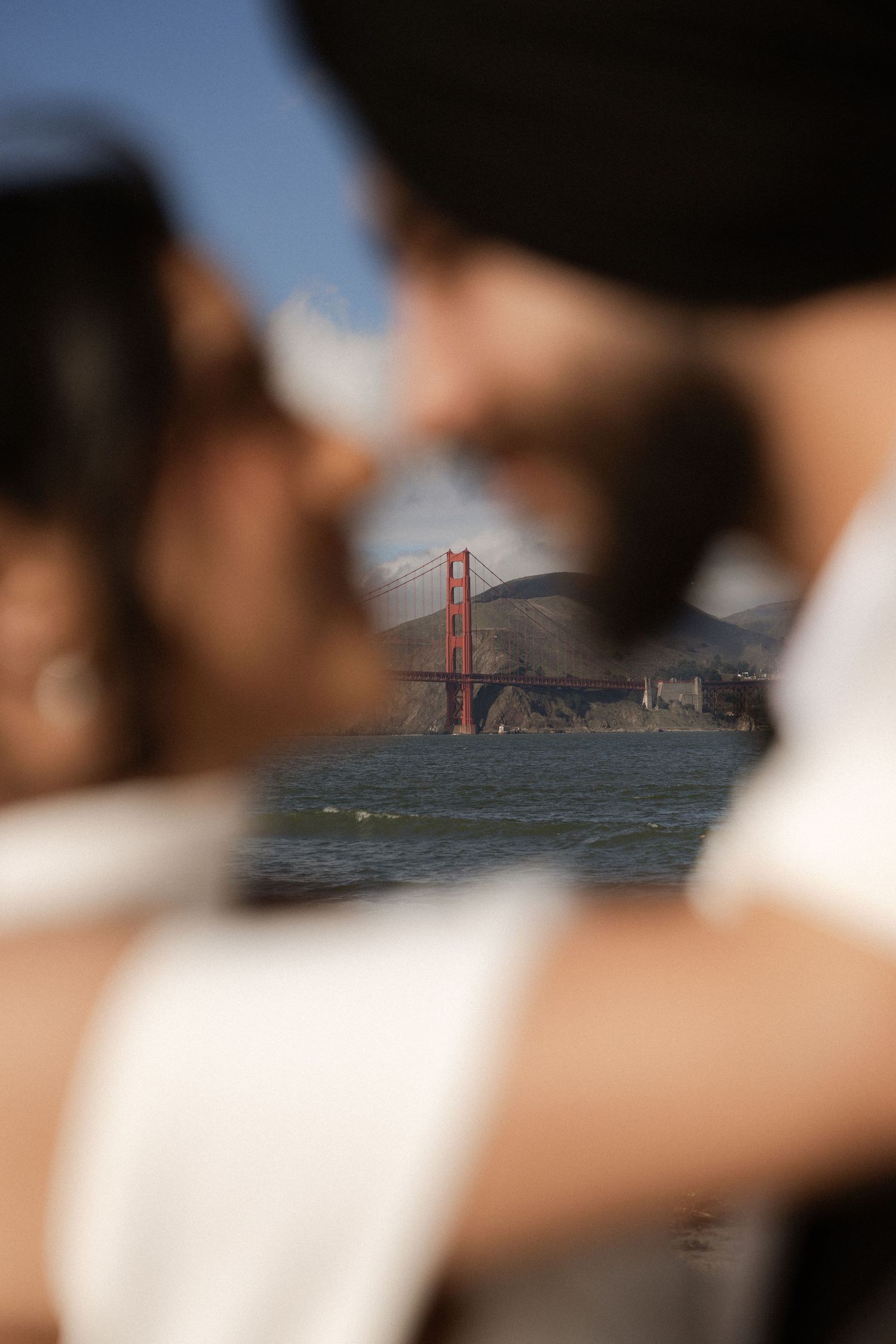 Blurred foreground with Golden Gate Bridge visible in distance across San Francisco Bay on foggy day.