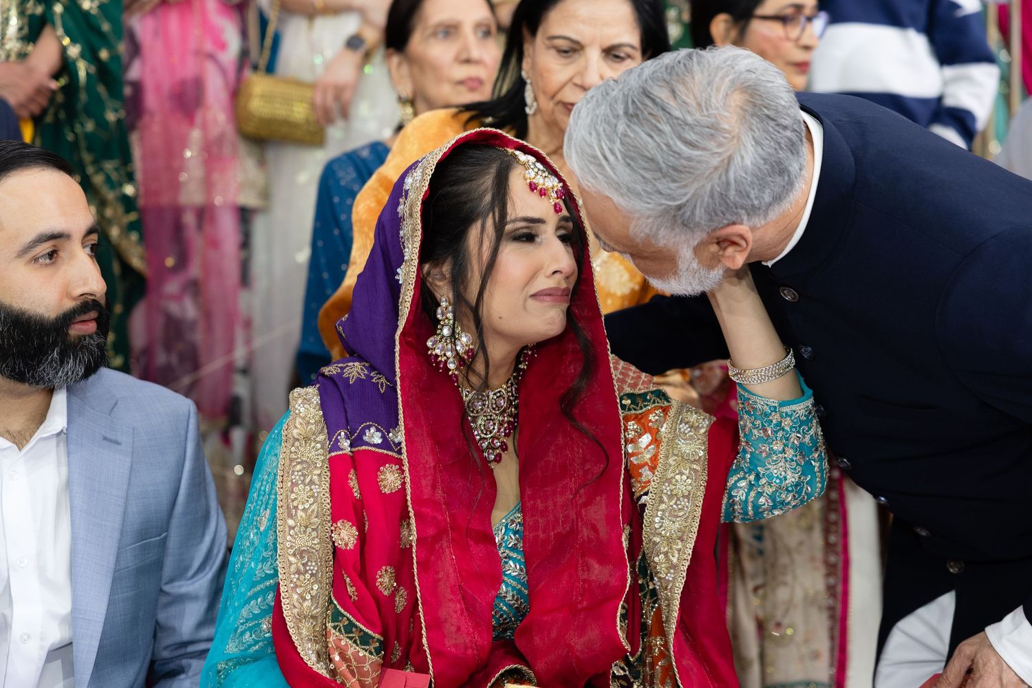 Wedding guests in traditional South Asian formal wear gathered at an elegant indoor celebration.