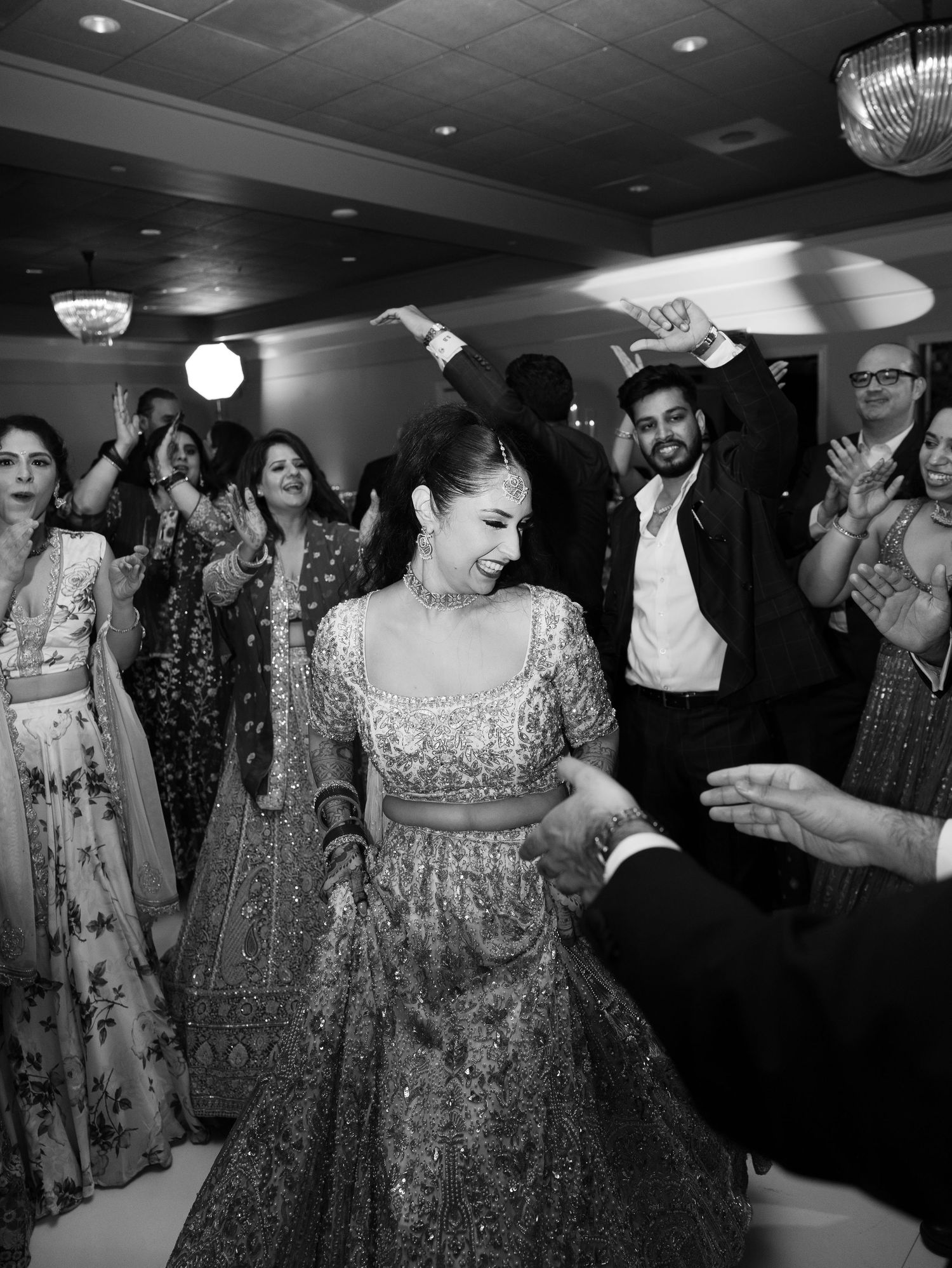 Wedding guests dance and celebrate together on a dimly lit dance floor at a reception.