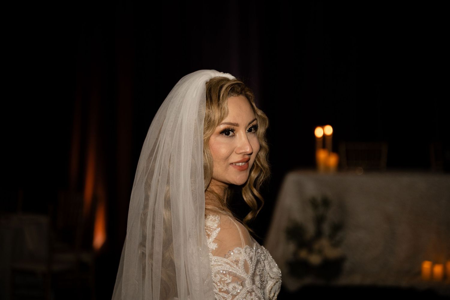 Close-up shots of an elegant wedding gown with lace details and long sleeves in dim lighting.