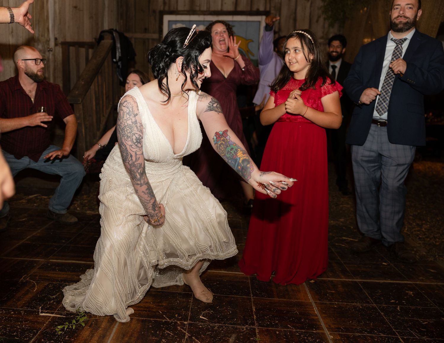 Wedding guests dance and celebrate in a rustic barn venue with wooden walls.