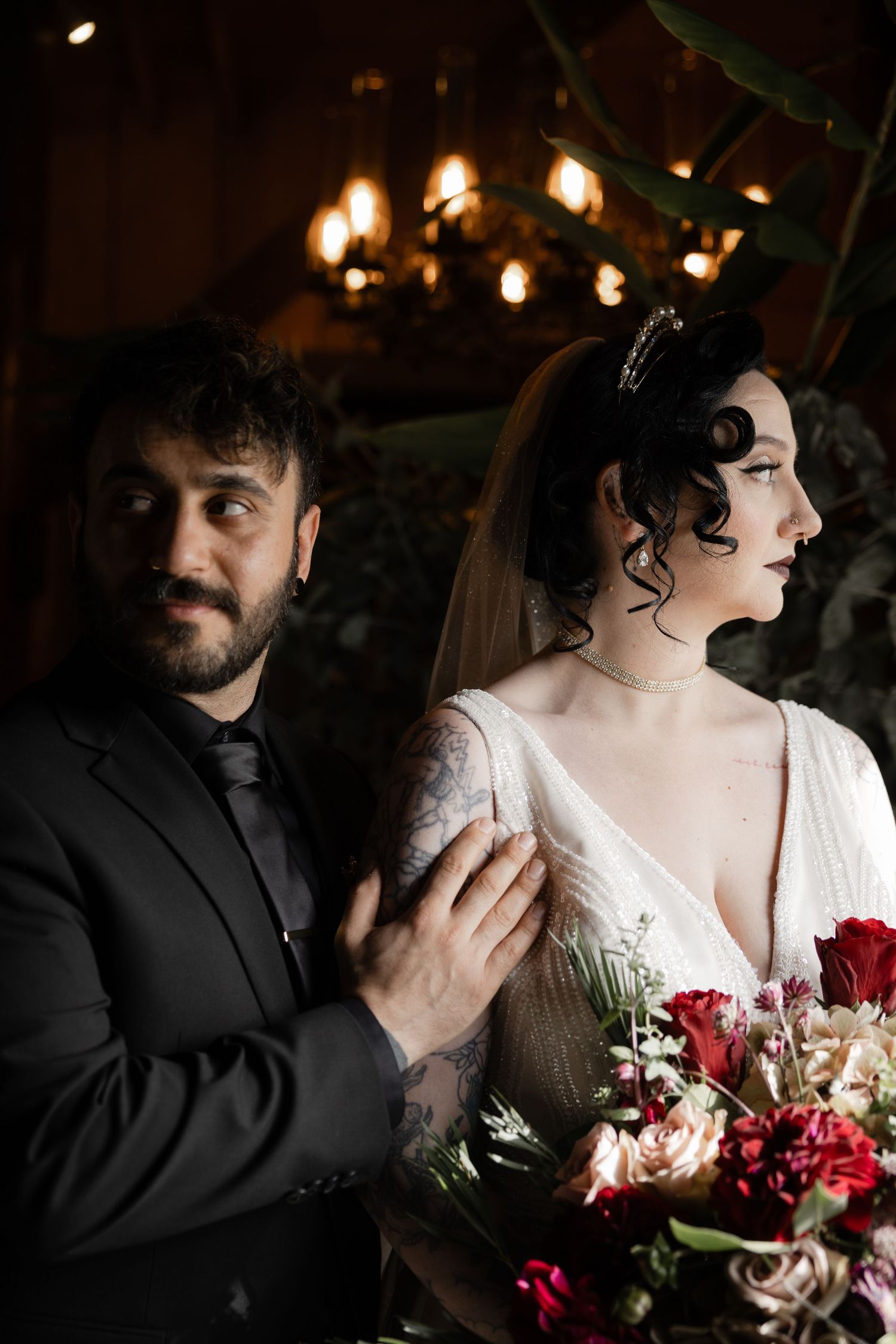 Moody wedding portrait featuring couple in black and white attire with dramatic lighting.