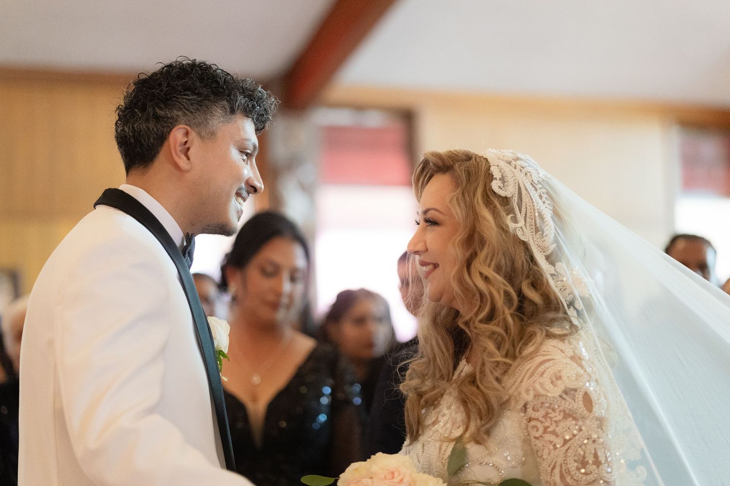 Wedding celebration with guests in formal attire interacting in church setting.