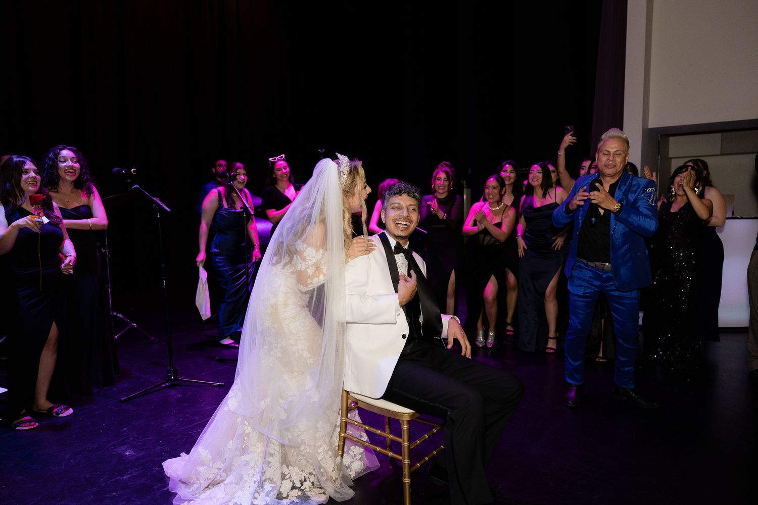 Wedding celebration with guests dancing under purple mood lighting in a reception hall.