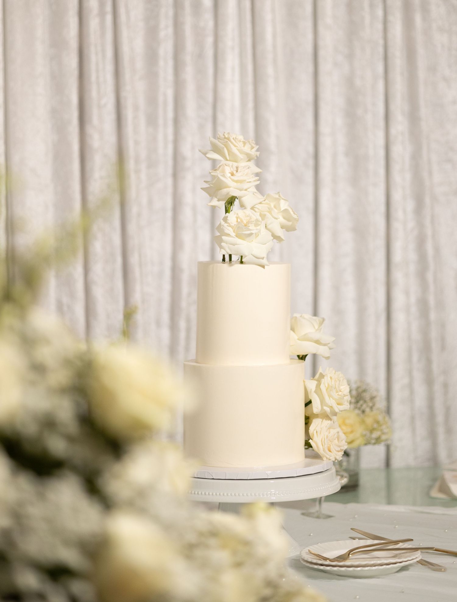 Elegant white wedding cake displayed against soft white draping.