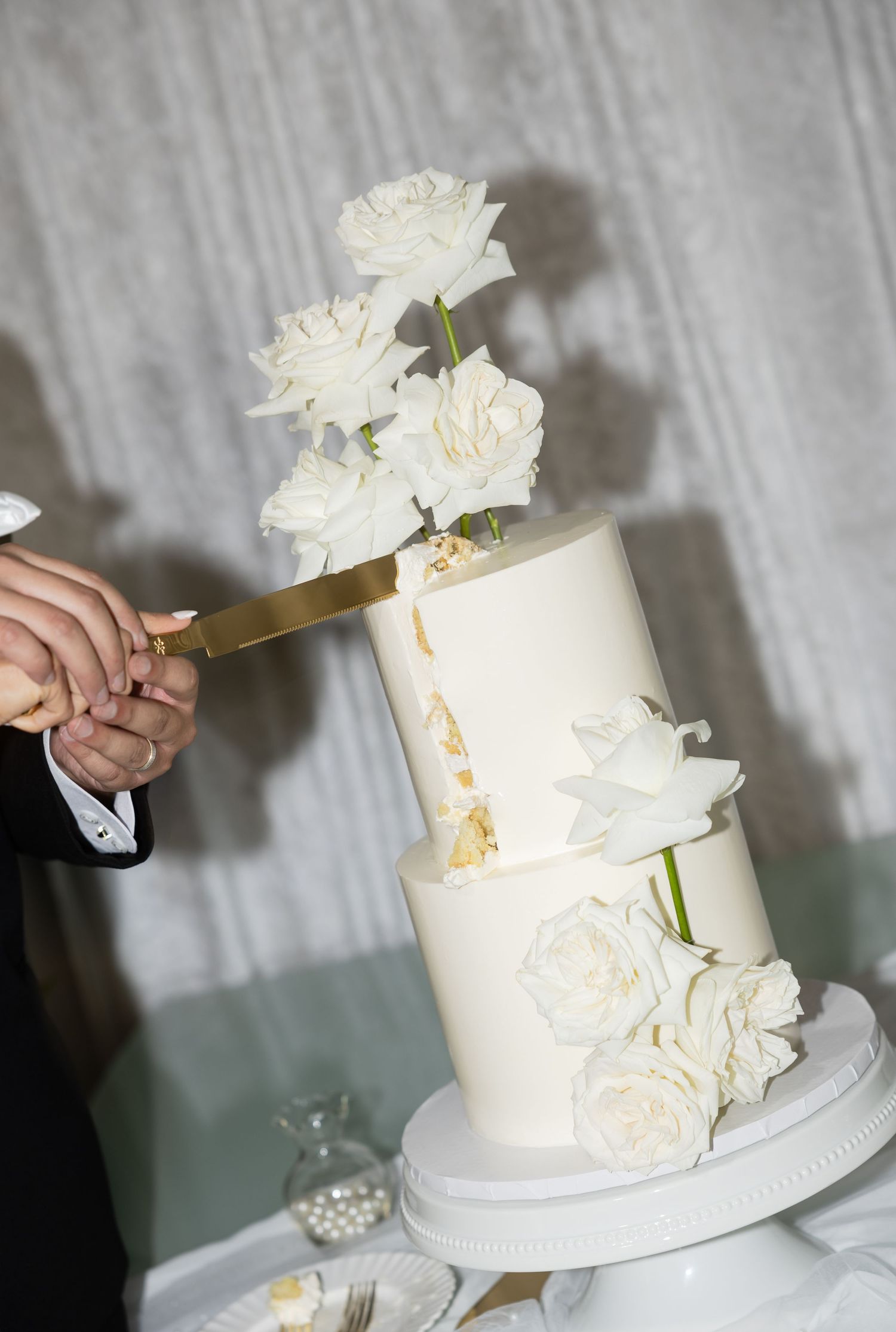 Detailed shots of an elegant white tiered wedding cake decorated with fresh flowers.