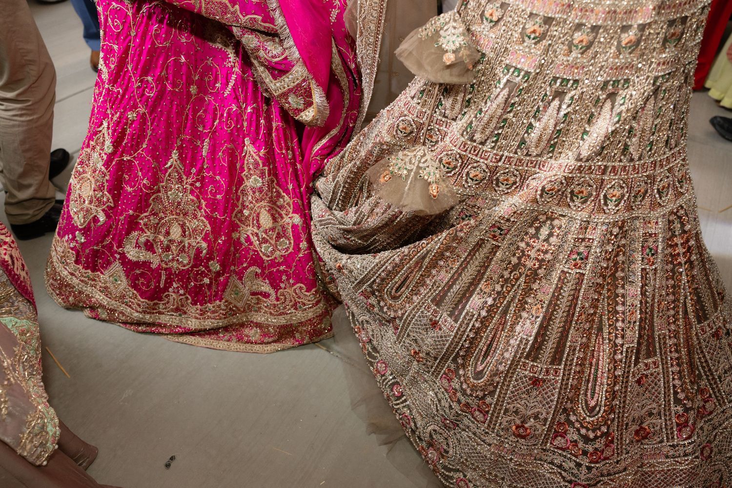 Ornate pink and gold Indian wedding lehengas with intricate embroidery and beadwork displayed in a row.