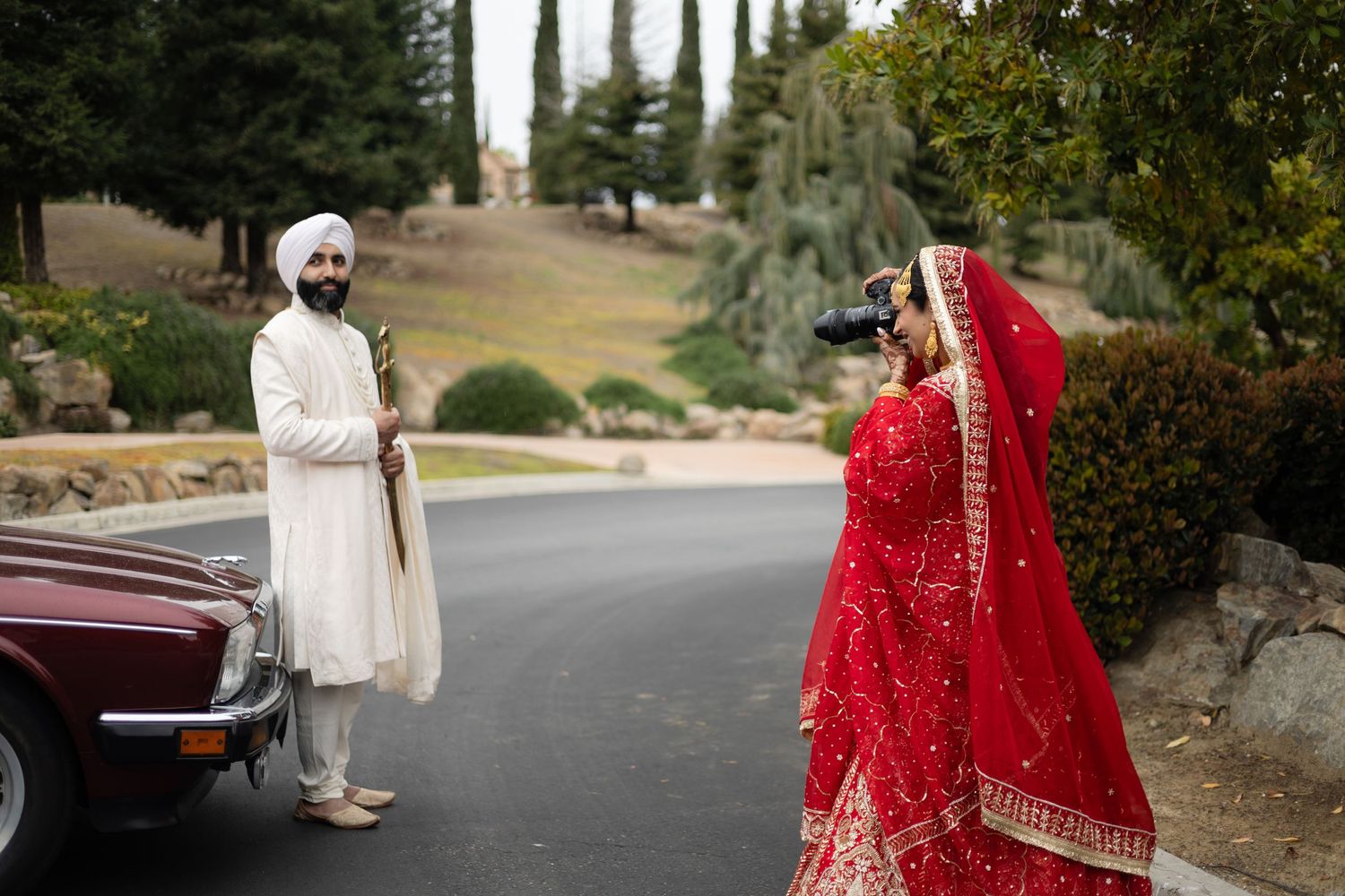 Outdoor wedding photography session featuring traditional South Asian bridal attire in a garden setting.