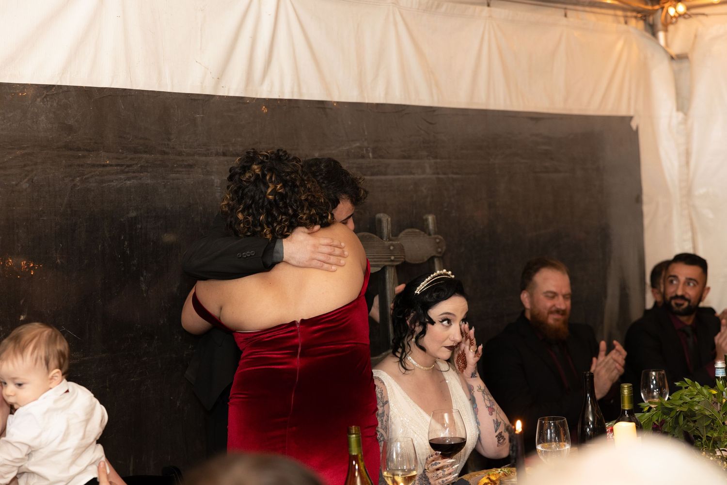 Wedding party dancing and celebrating in a rustic barn venue with string lights overhead.