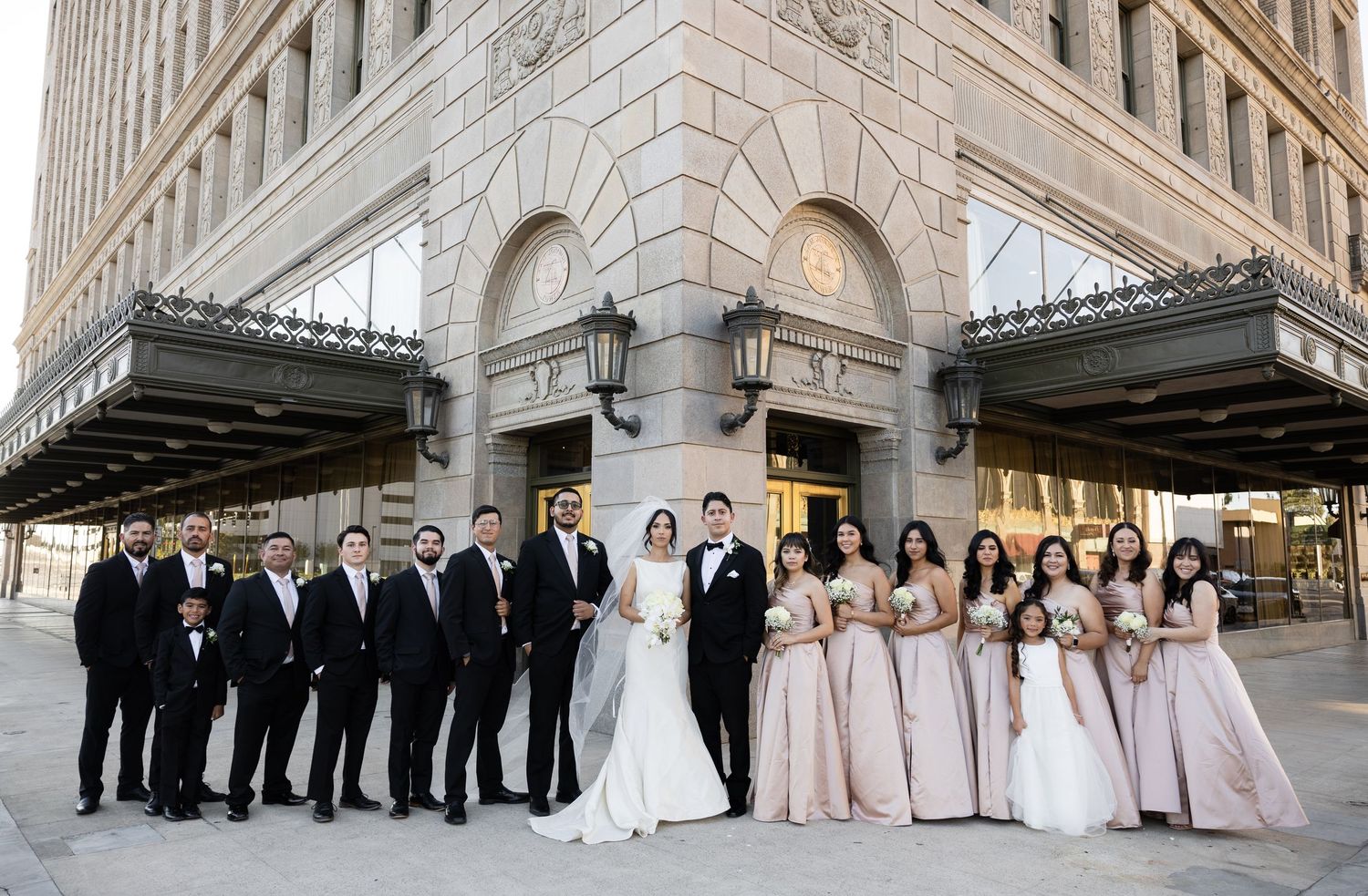 Panoramic view of wedding party lined up against stone architecture.