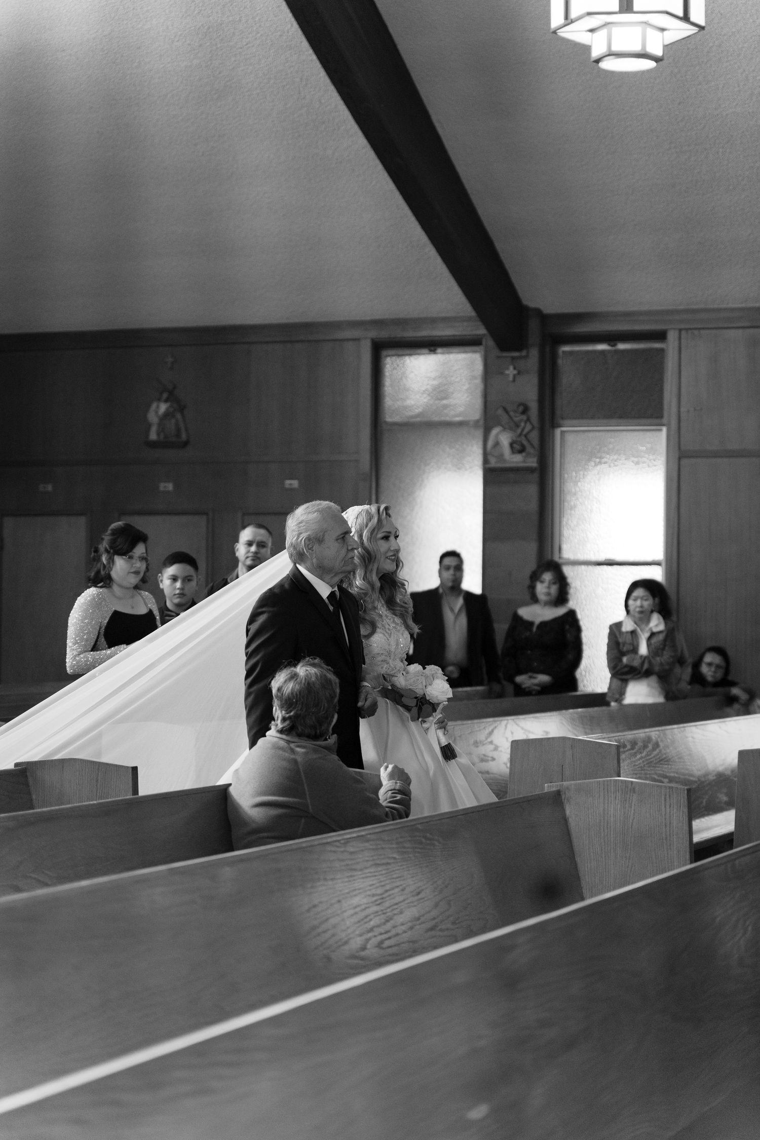 A black and white photograph of a wedding ceremony taking place in a traditional church setting.
