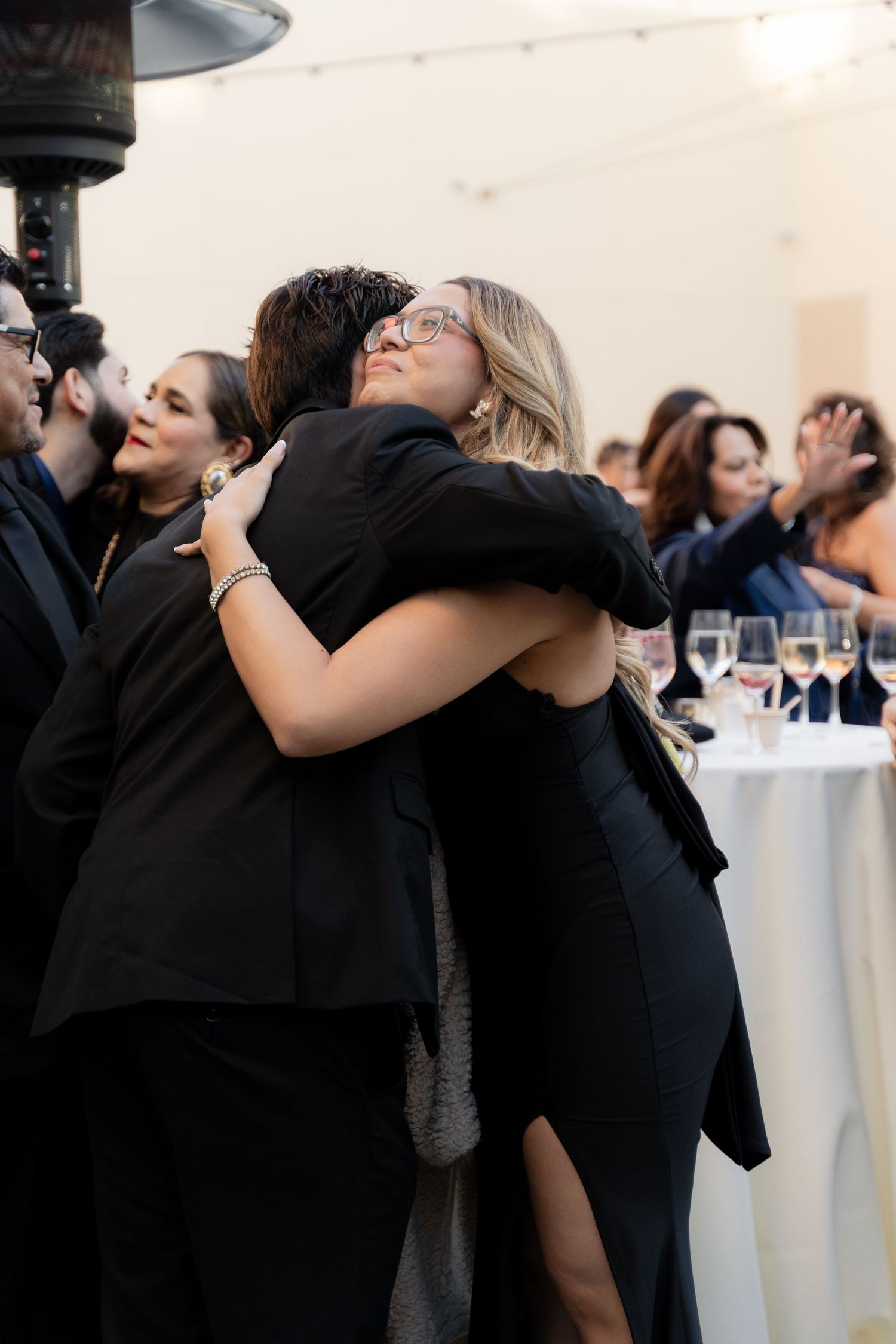 Wedding guests share emotional embraces during reception celebration.
