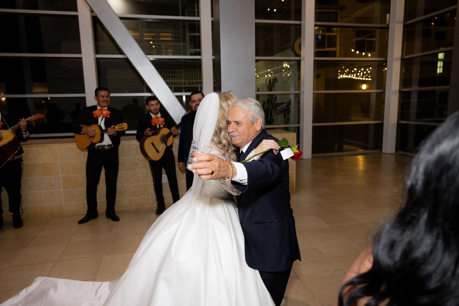 A couple embraces during their wedding dance while musicians perform in the background.
