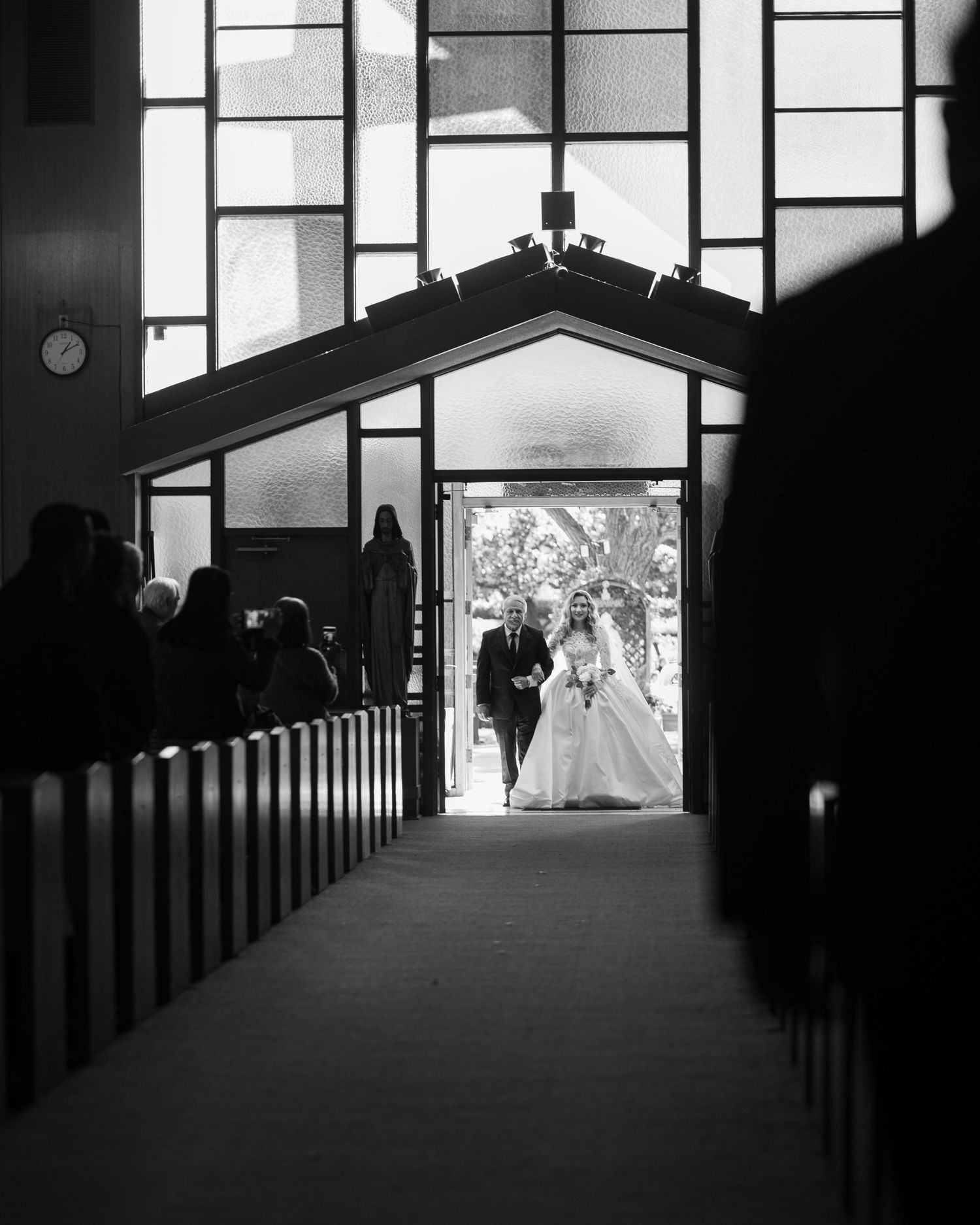 Black and white photo of a church interior with silhouetted figures and dramatic window lighting.