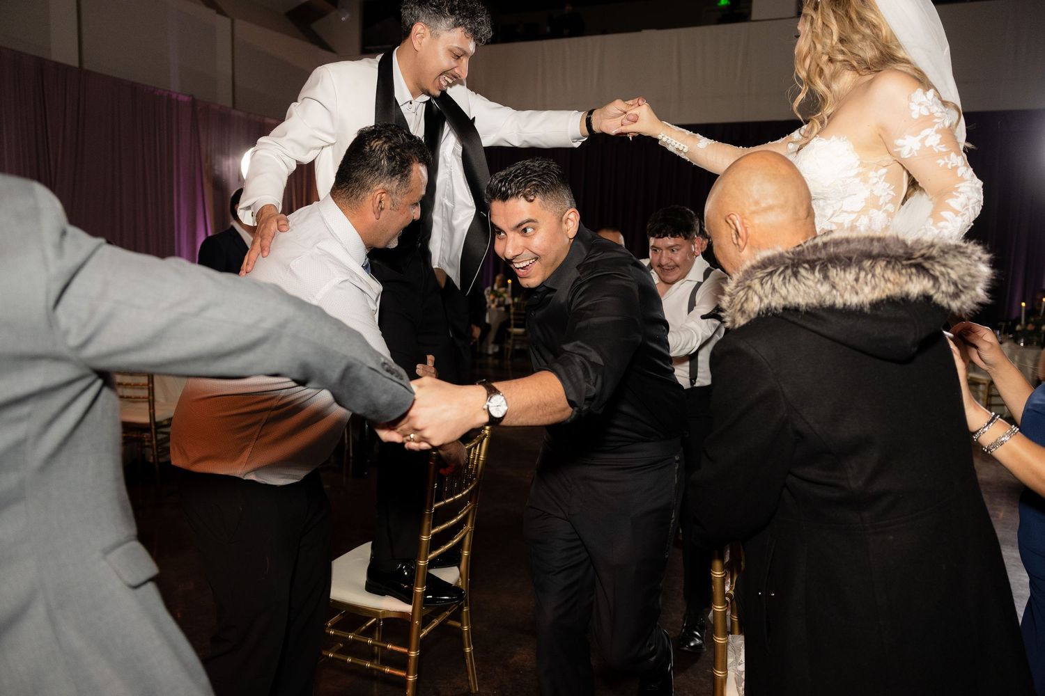 Wedding party members dance and interact playfully at the reception.