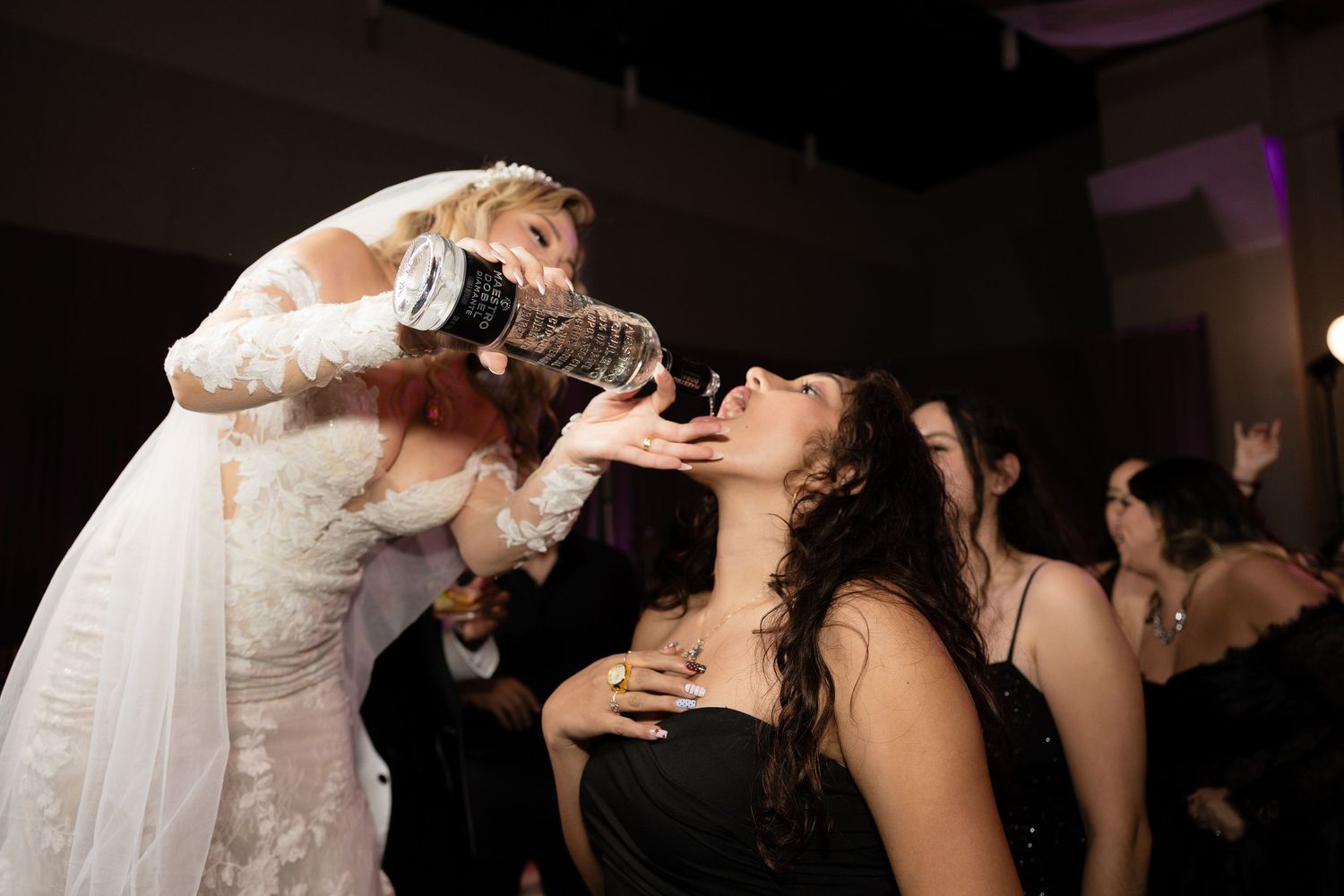 A bride pouring drinks for guests during wedding reception festivities.