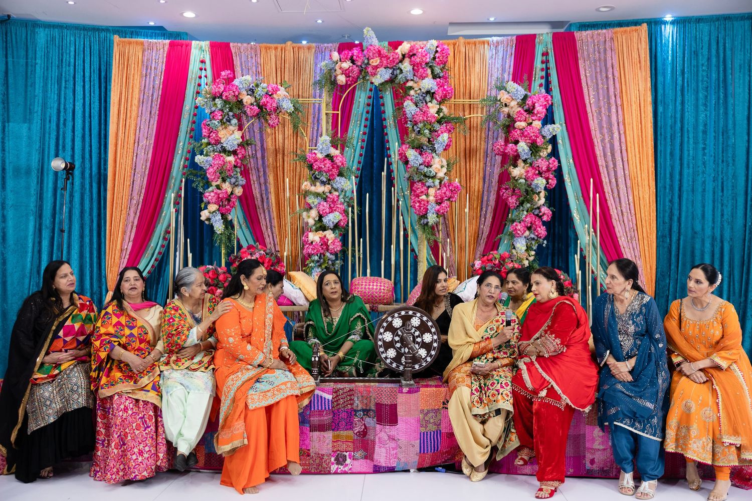 A colorful Indian wedding ceremony setup with bright turquoise and pink drapes decorated with floral arrangements.
