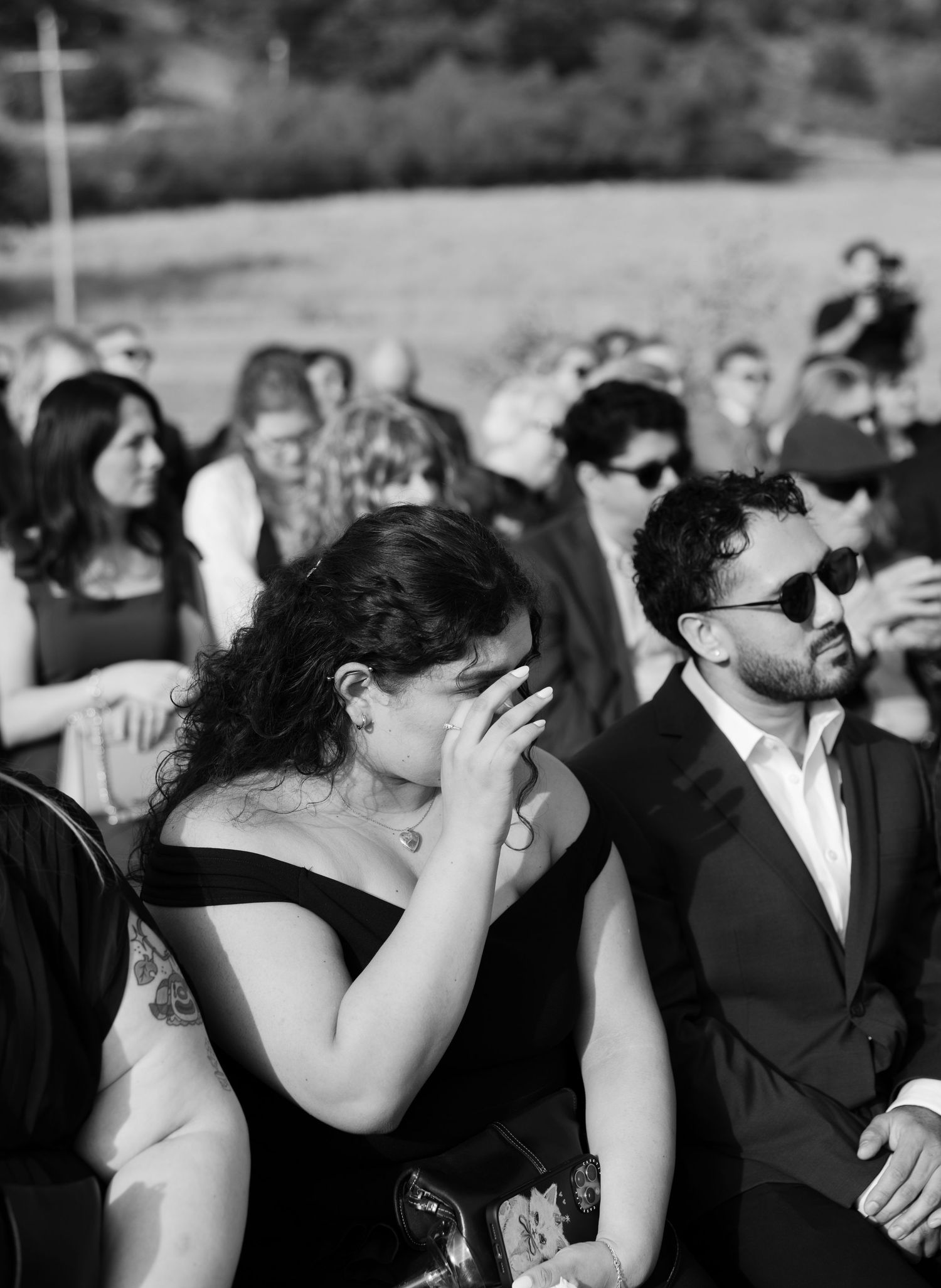 Black and white photo of wedding guests watching the ceremony with emotional expressions.