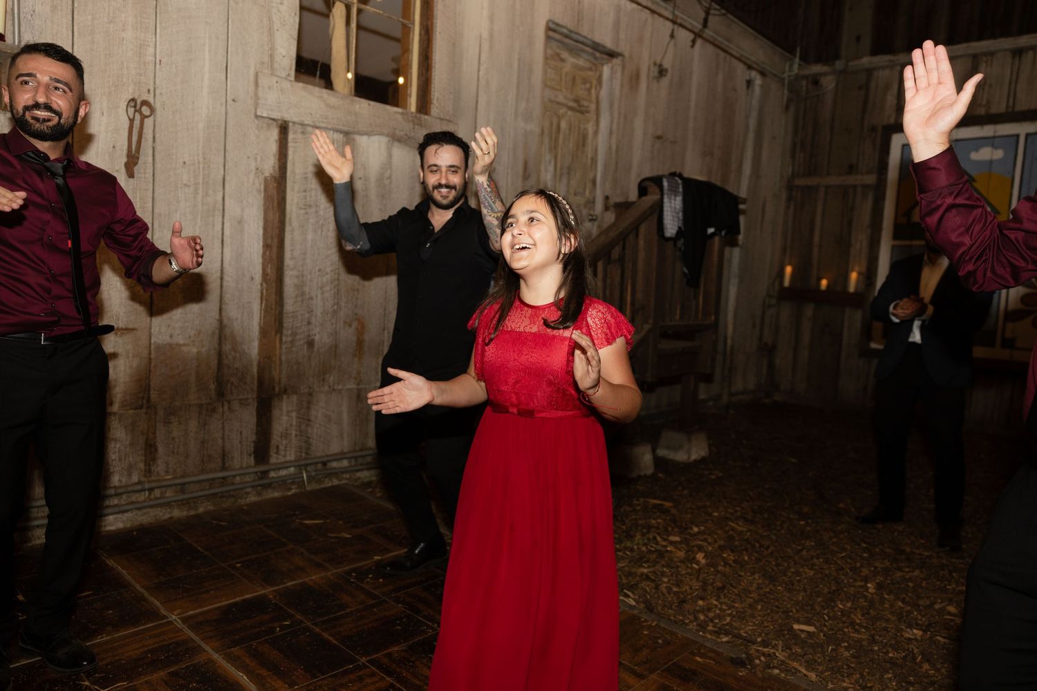Guests celebrate with energetic dancing at a rustic indoor wedding reception.