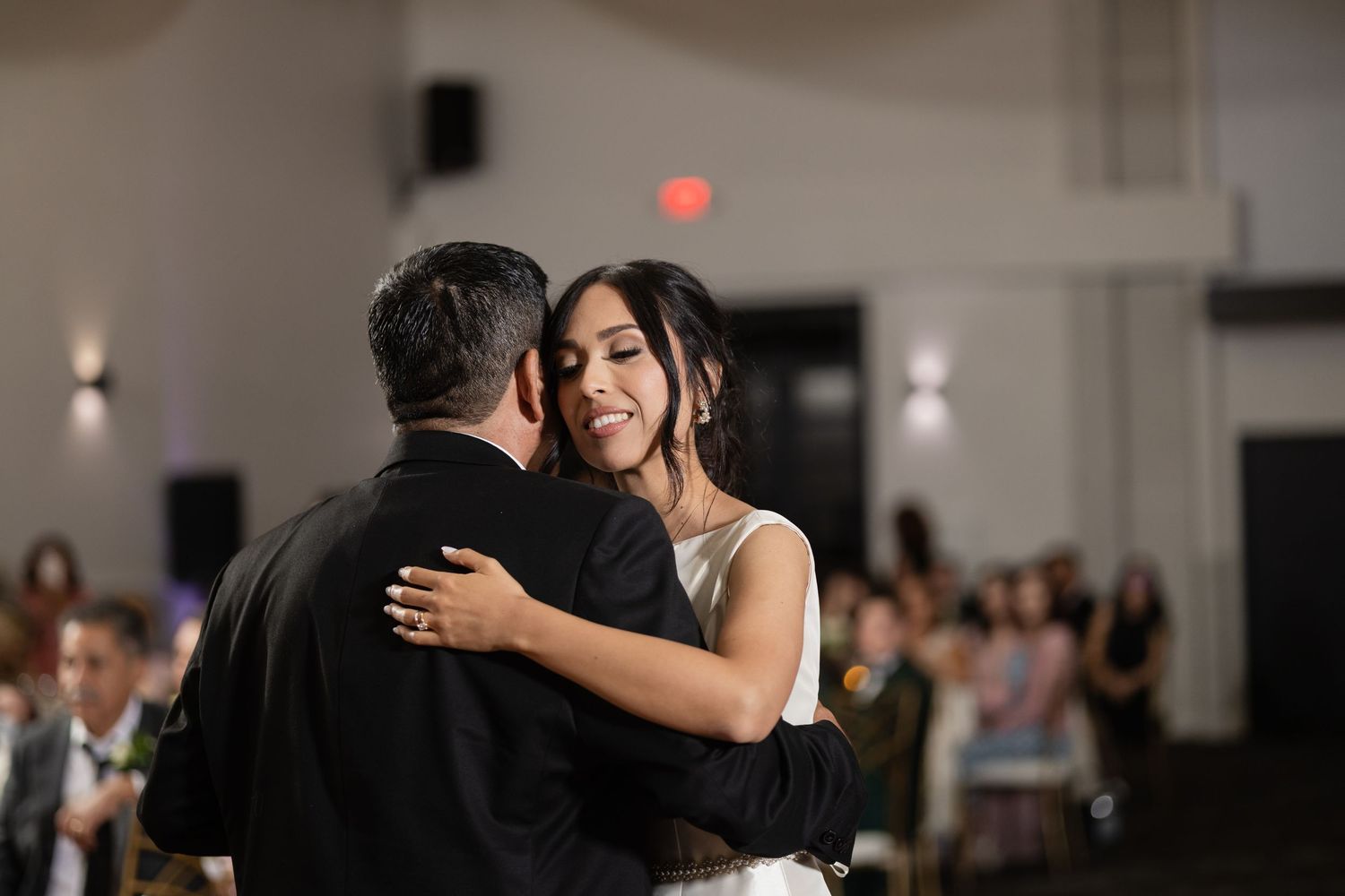 Couples dancing together at an elegant indoor wedding reception with ambient lighting.