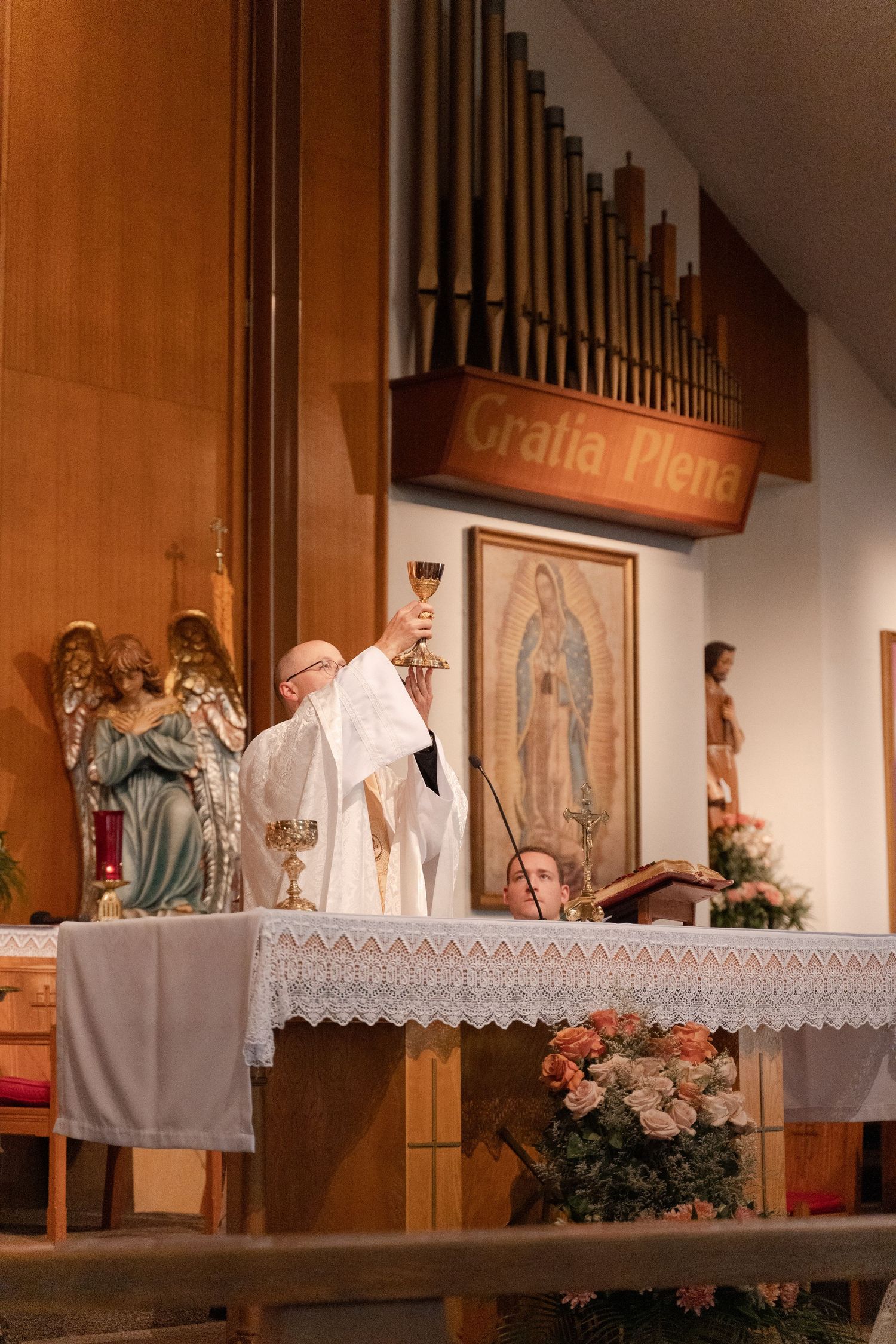Church sanctuary with wooden organ pipes and religious artwork displayed on altar.