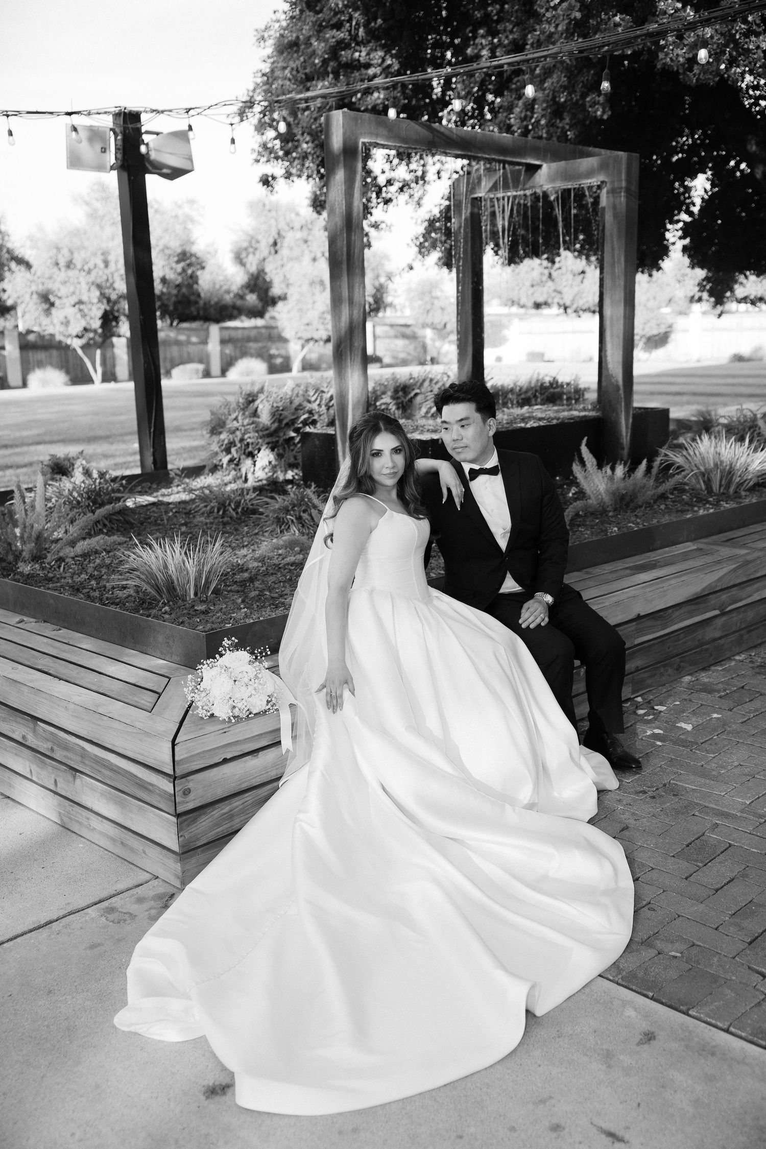 Bride and groom posing in black and white photo at outdoor wedding venue.