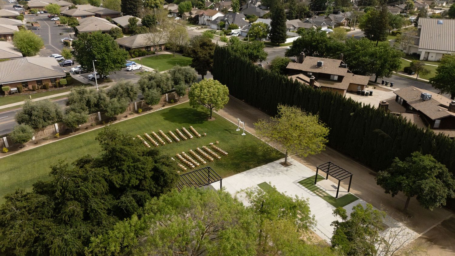 Aerial drone view of outdoor wedding venue with rows of chairs on green lawn.