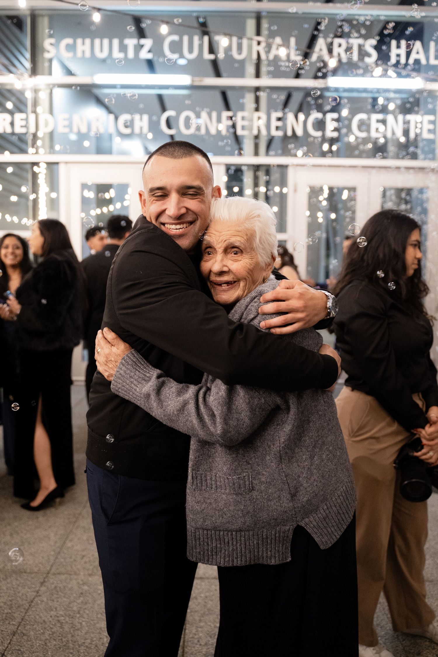 Joyful guests embrace and celebrate at a formal event in the Schultz Cultural Arts Hall.