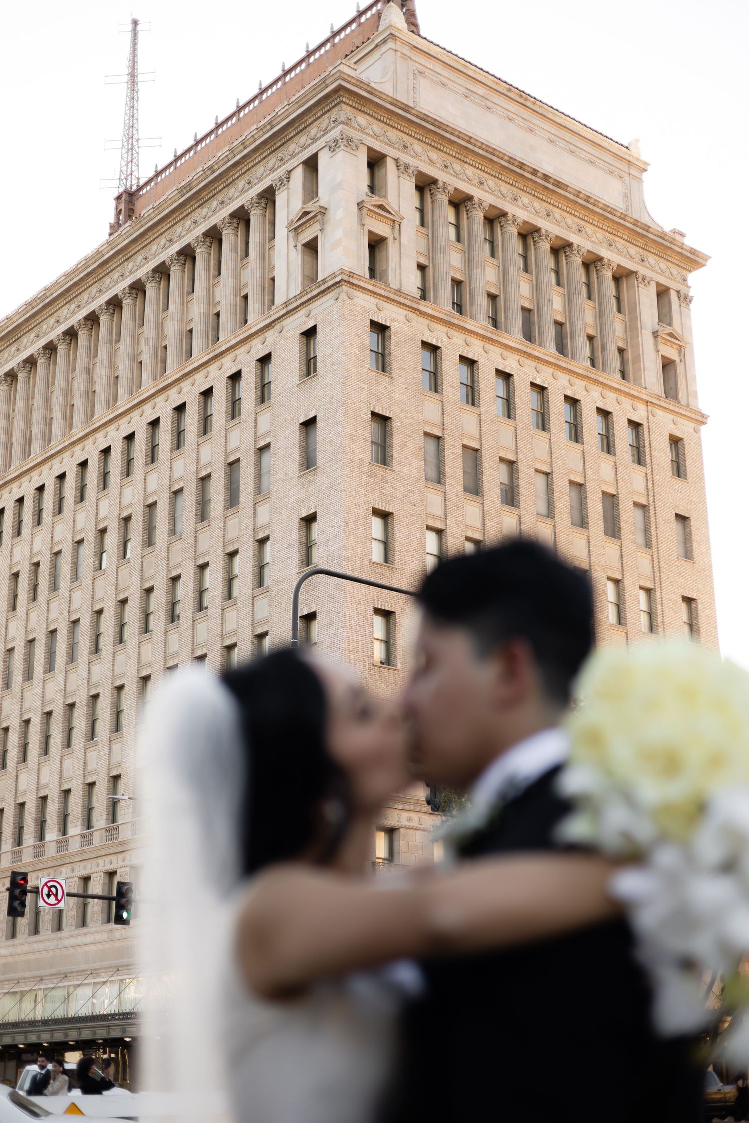 Wedding couple embraces in front of a grand historic building during their romantic photoshoot.