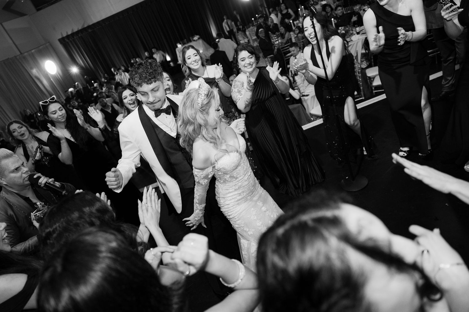 Wedding party guests dancing and mingling on a crowded dance floor in black and white.