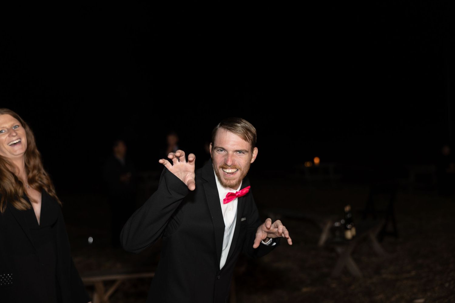 Dark reception venue with guests celebrating and raising hands in joy.