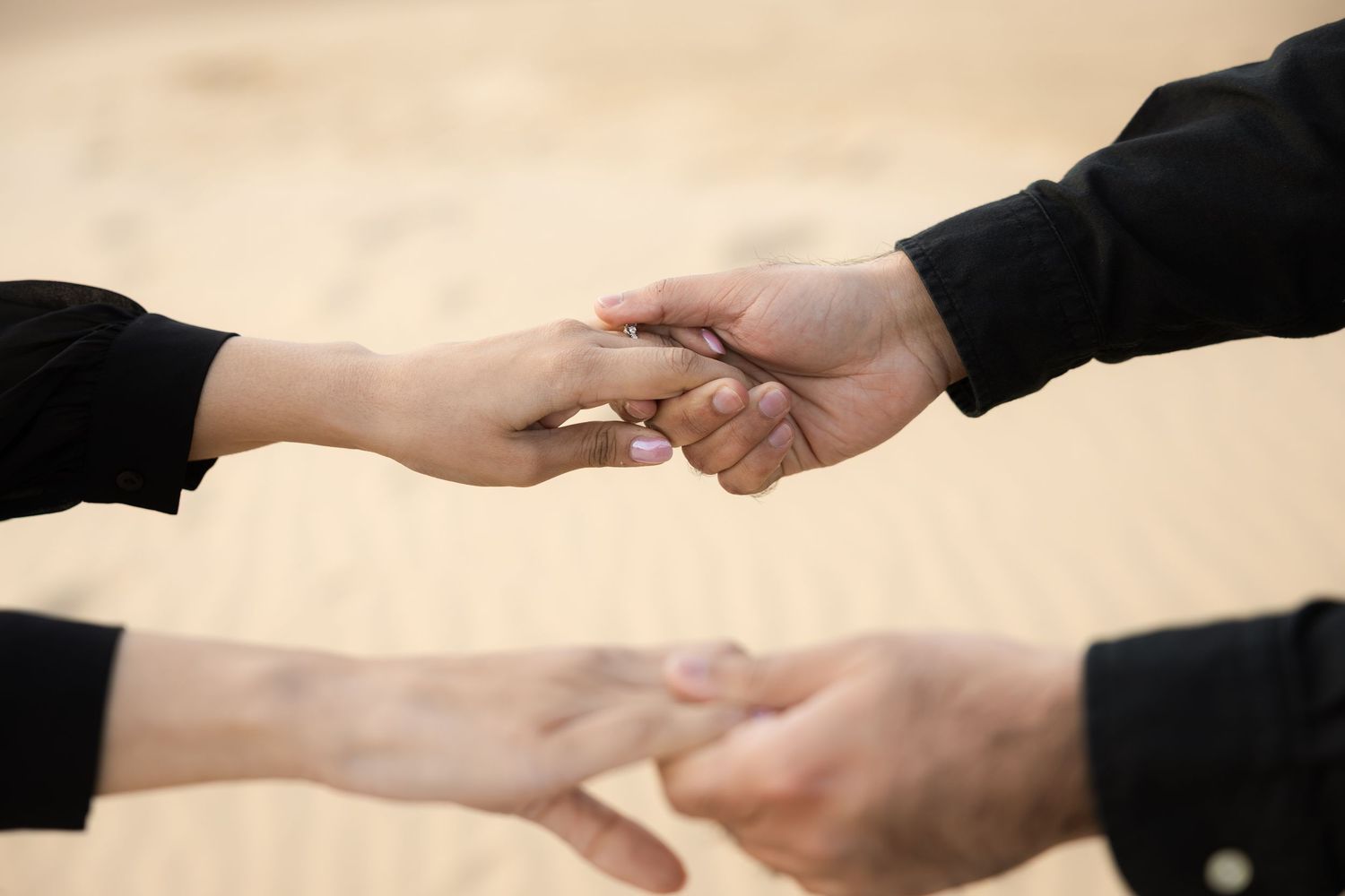Two hands reaching out to hold each other gently against a neutral background.