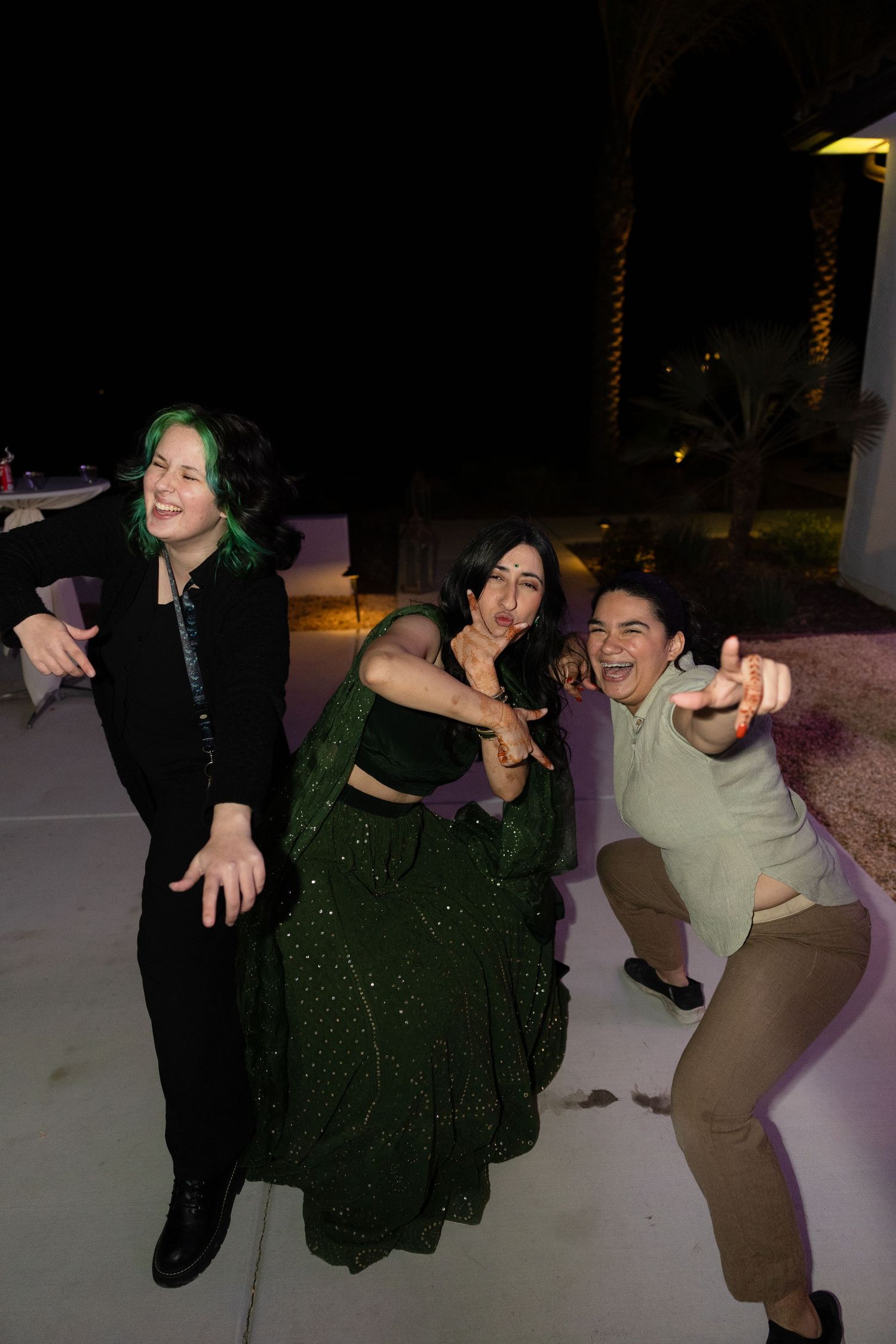 A group of people dance and pose together in a dark outdoor setting at night.