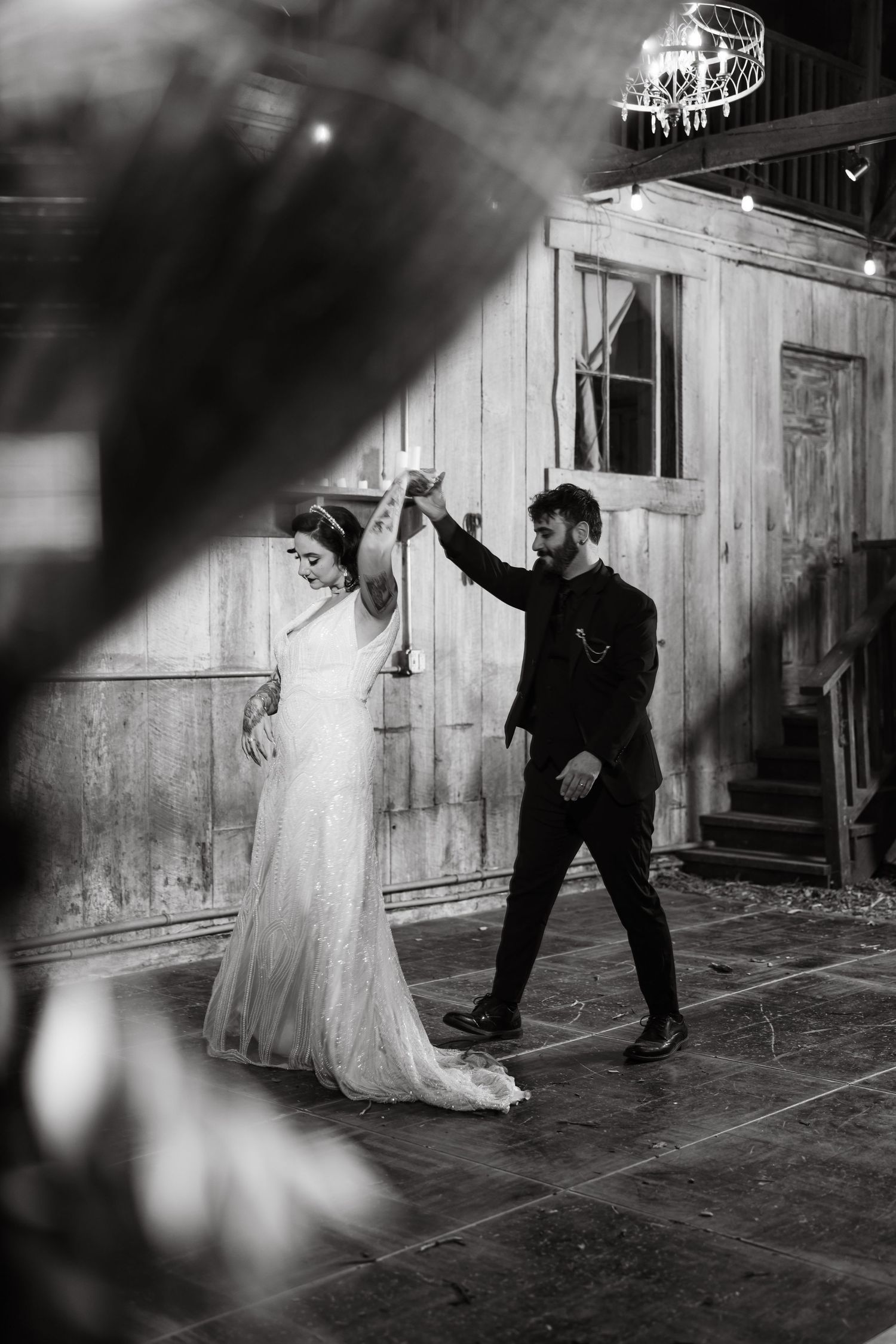 Black and white sequence of a wedding dance in a rustic barn setting with dramatic lighting.