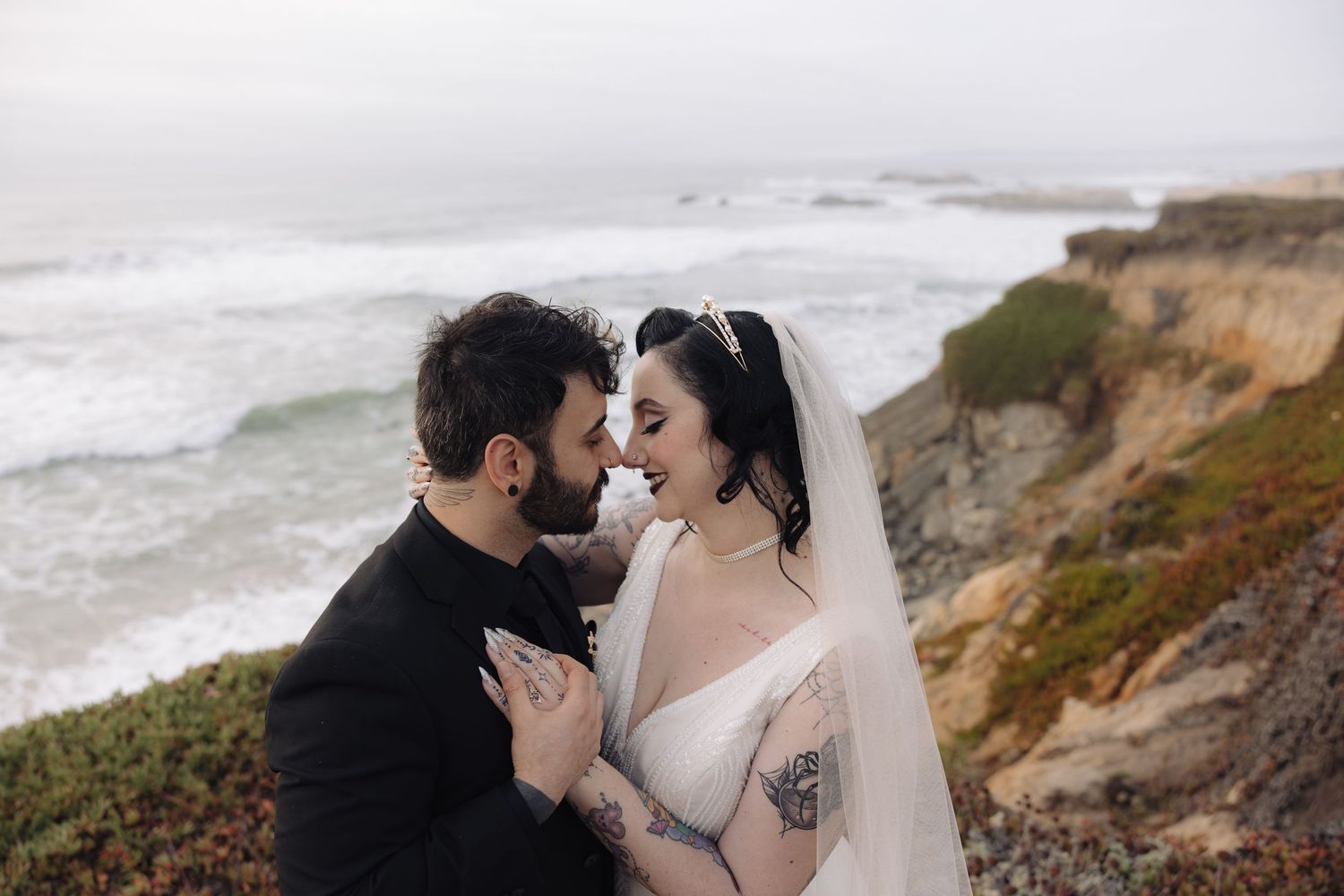 Emotional wedding portrait captured against dramatic coastal scenery and overcast skies.