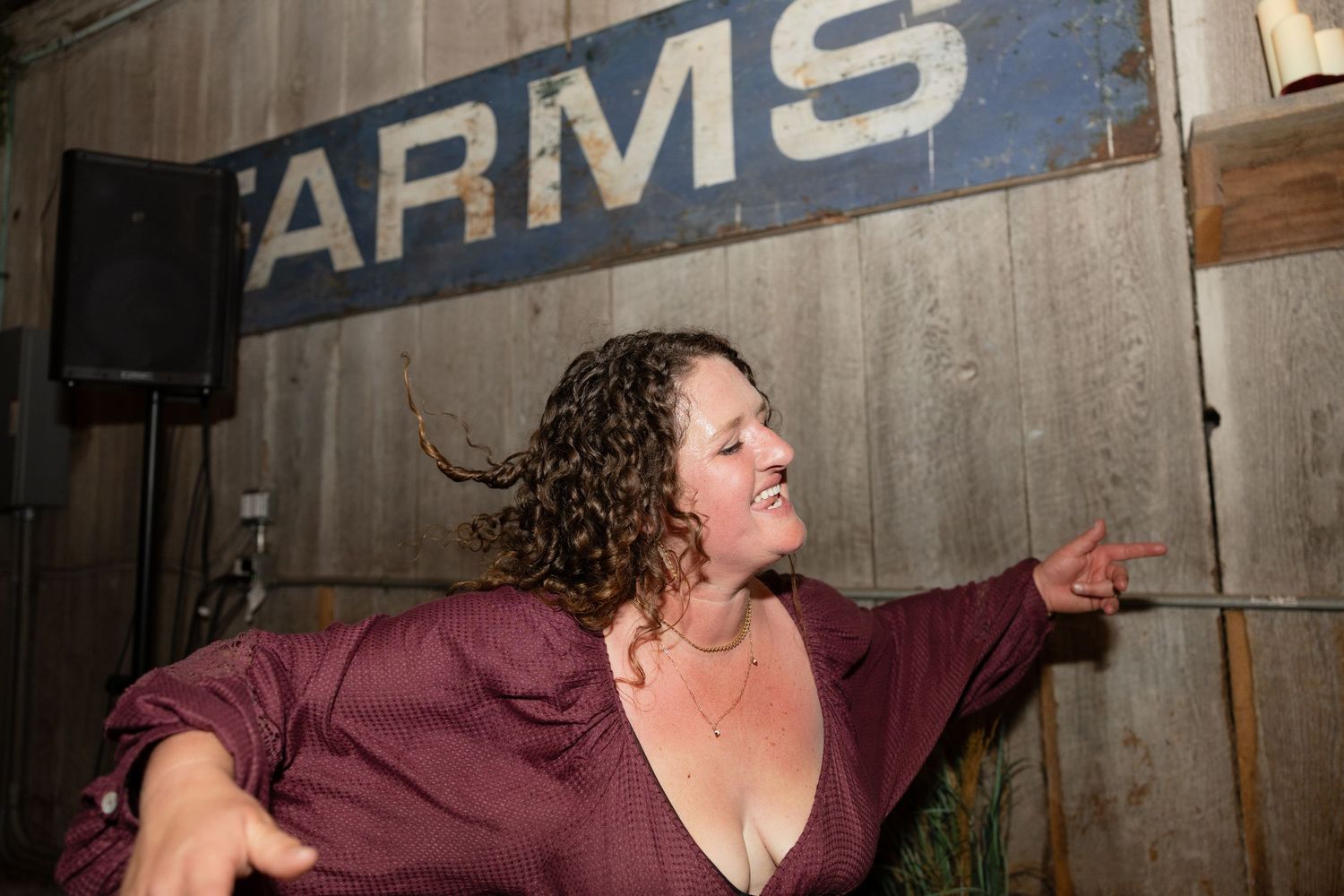 Energetic dancing and celebrations at a rustic barn wedding venue with industrial signage.