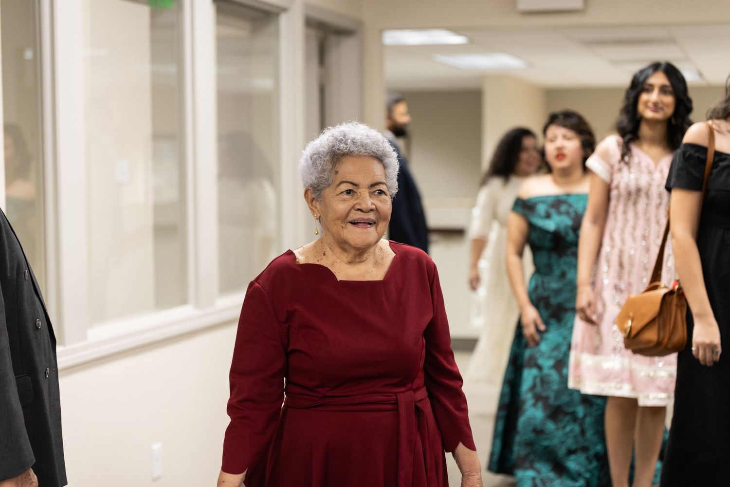 People walking down a brightly lit hallway during a formal event.
