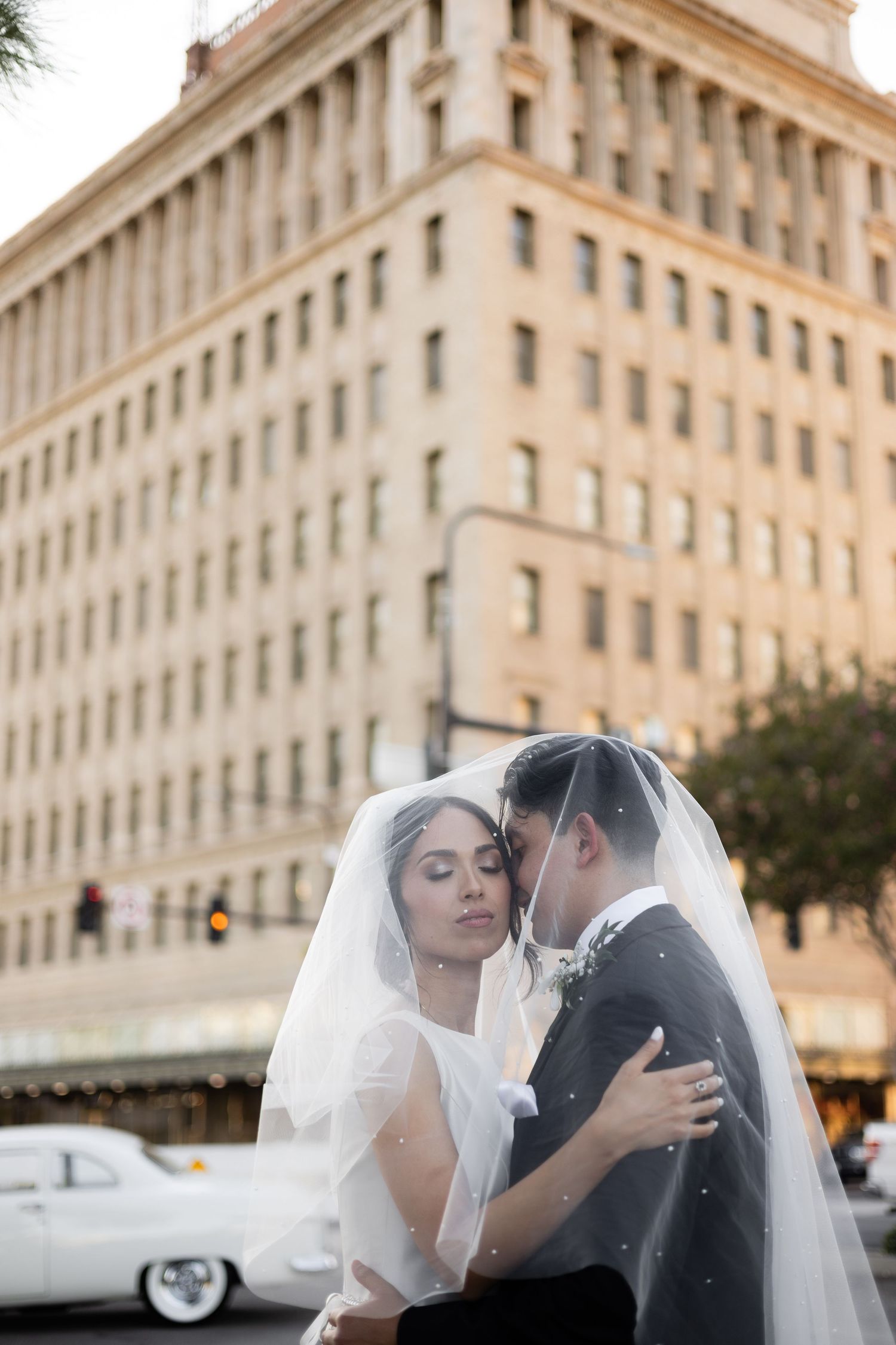 Romantic wedding photos taken at sunset against a beautiful stone building facade.