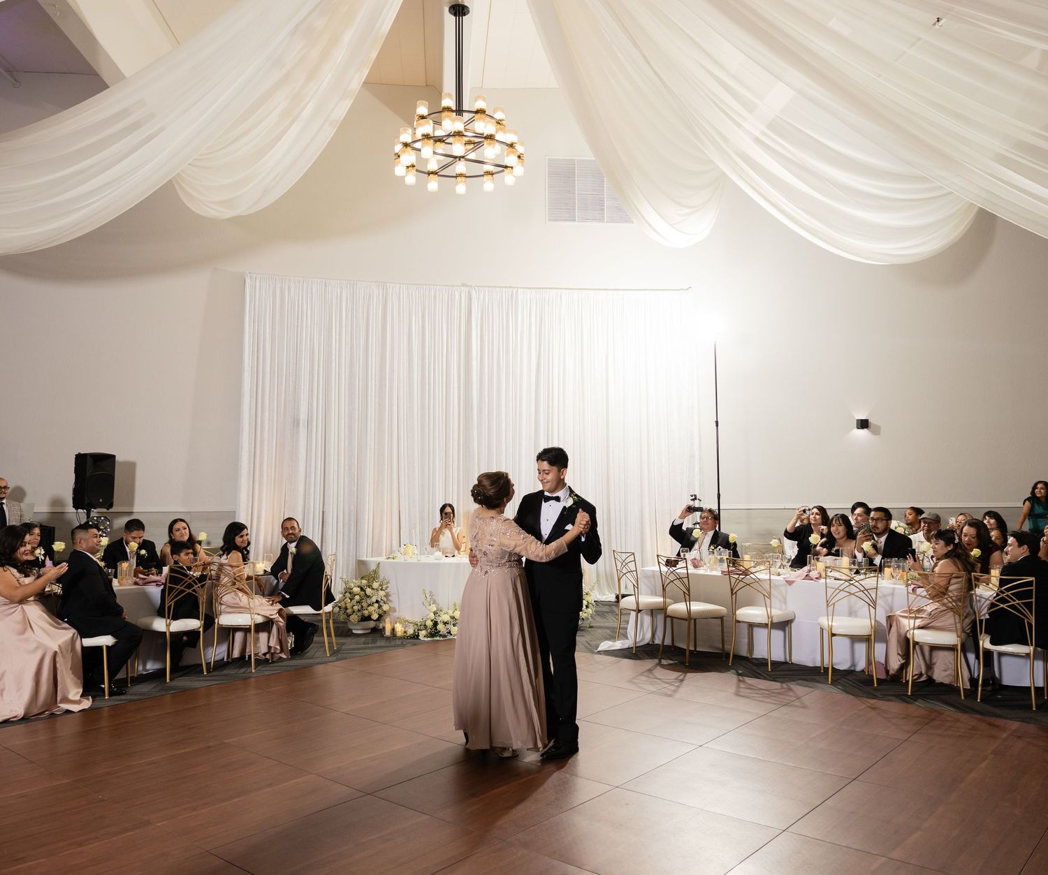 Wedding venue decorated with white fabric ceiling treatments and elegant lighting.