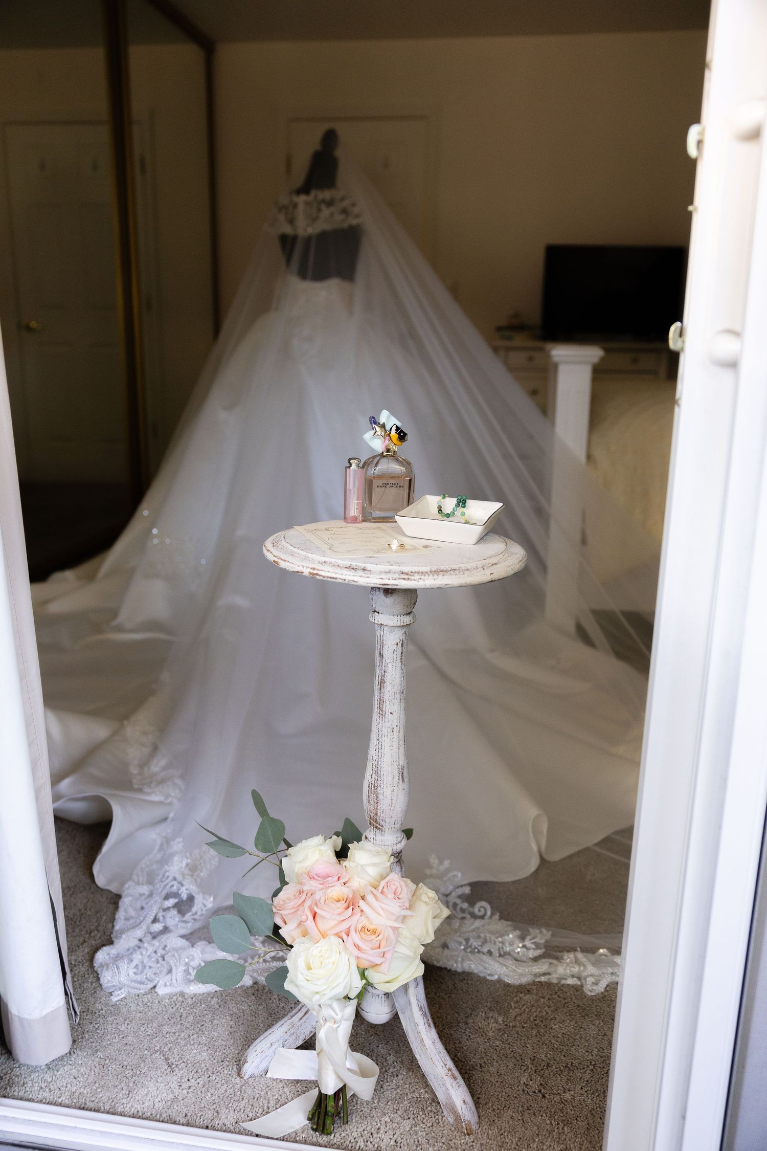 White wedding dresses on display with delicate pink floral bouquets and lace details.