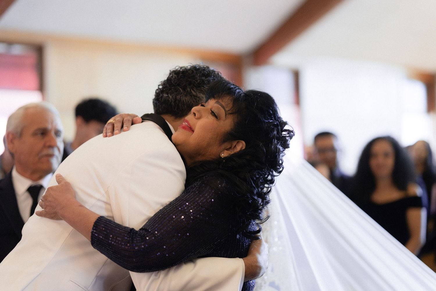 Wedding ceremony attendees embracing in emotional moment.