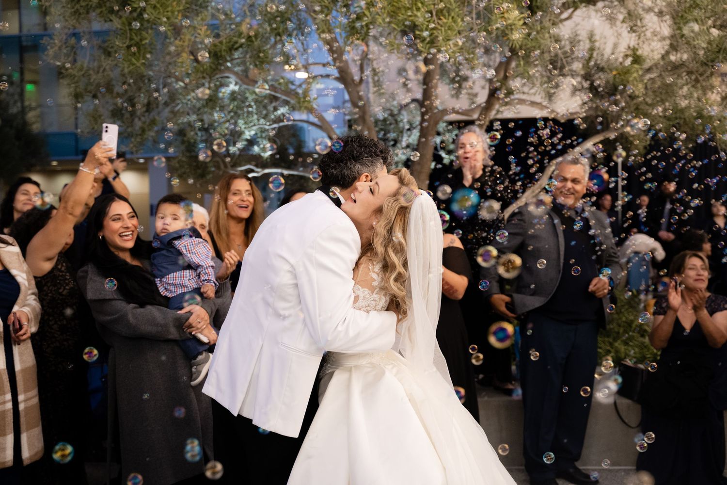 Wedding couple dances together surrounded by bubbles and cheering guests.