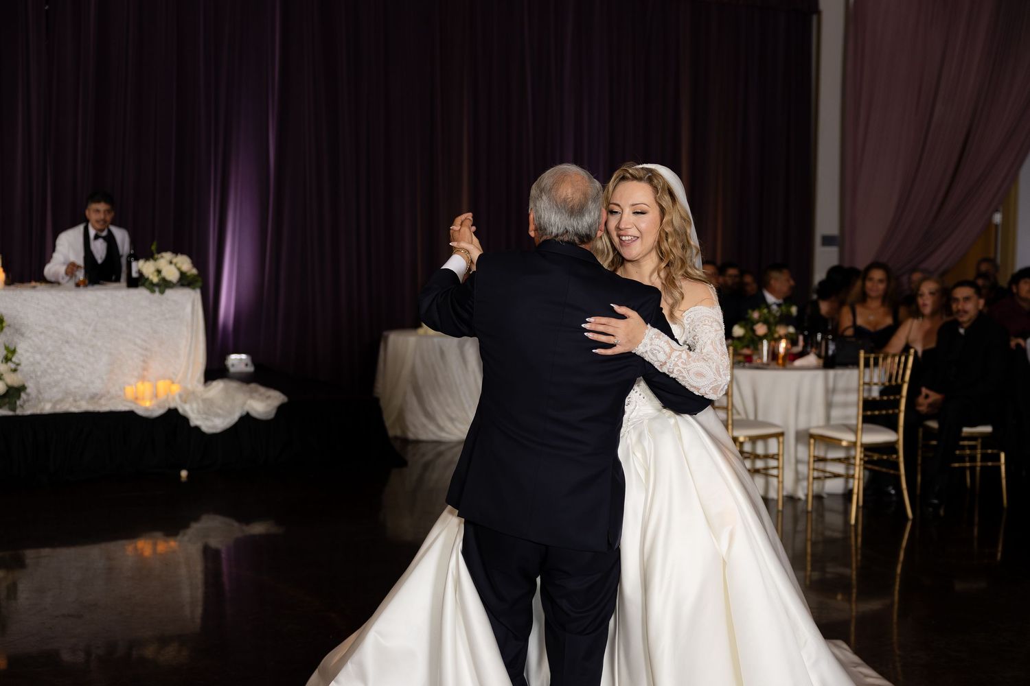 Traditional father-daughter dance at wedding reception with elegant white ballgown.