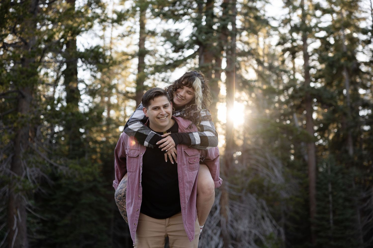 Romantic forest photoshoot with golden sunlight streaming through pine trees.