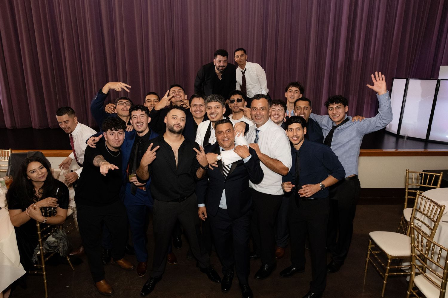 Large group photo of wedding guests posing together at the reception.