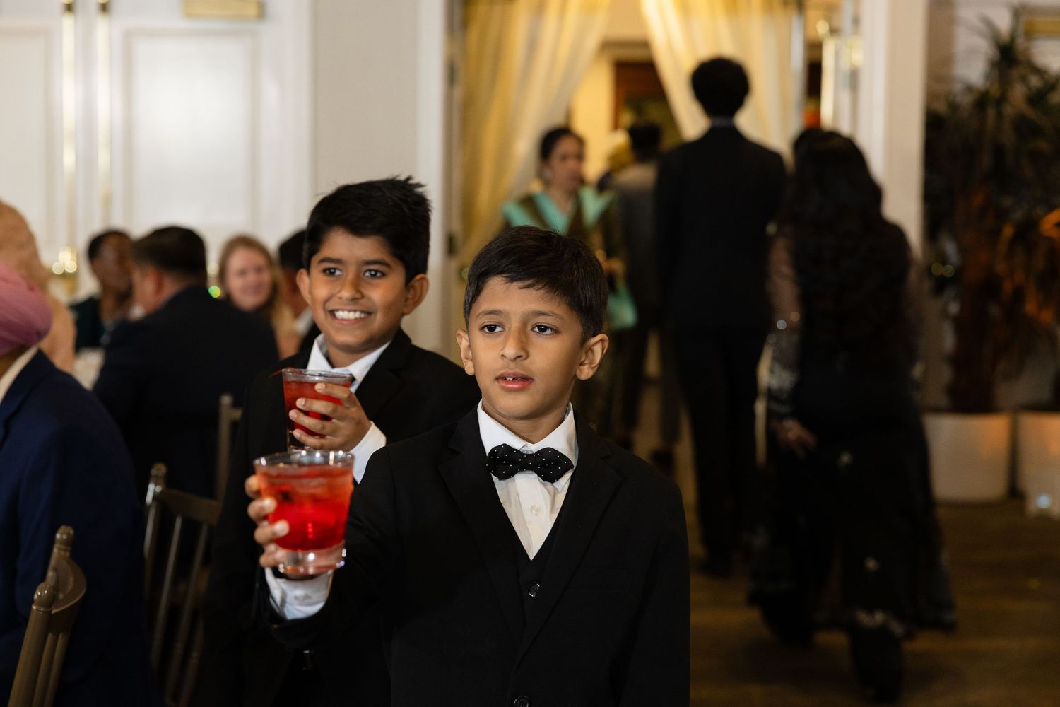 Young ring bearers in formal attire at an elegant indoor wedding ceremony.